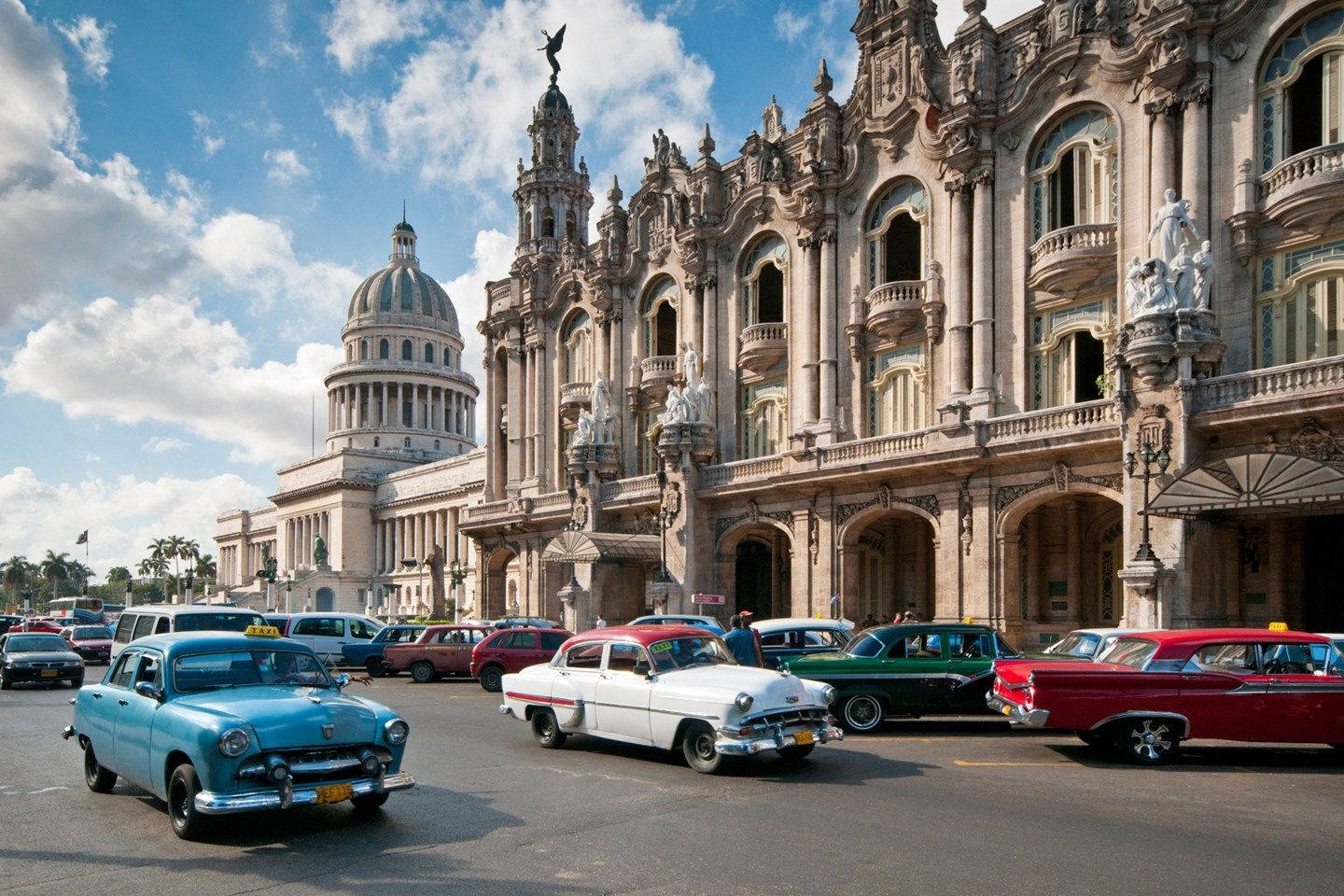 Cuba 桌布 壁紙 — 復古美國汽車在明亮的藍天白雲下，駛過華麗的新古典主義建築。