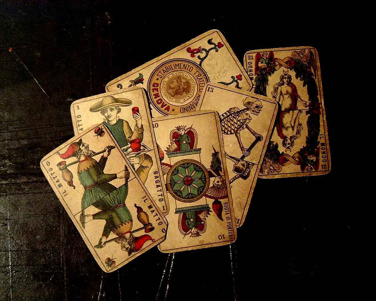Tarot Card 桌布 壁紙 — 復古義大利塔羅牌，帶有複雜插圖，散落在深色紋理表面上。