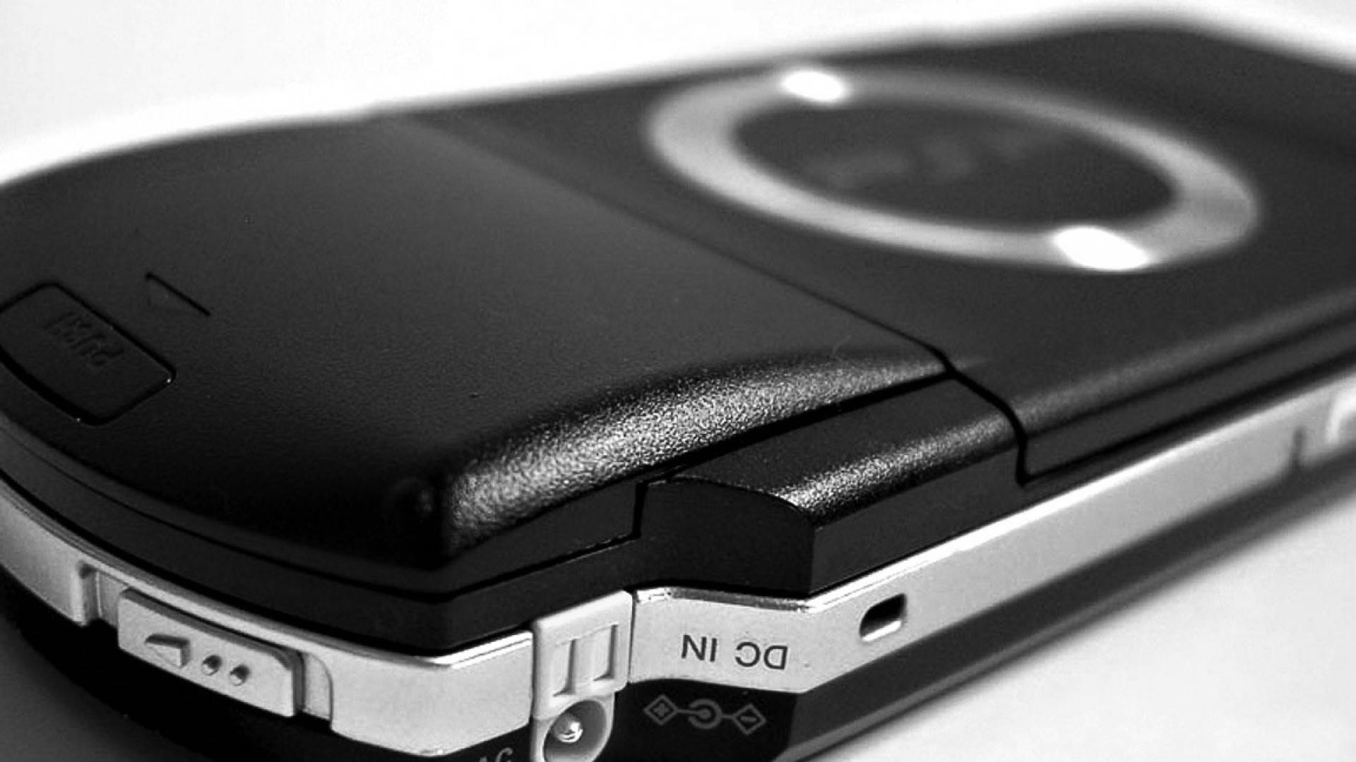 PlayStation 桌布 壁紙 — 復古翻蓋手機的黑色紋理外殼和銀色金屬邊緣的特寫黑白照片。