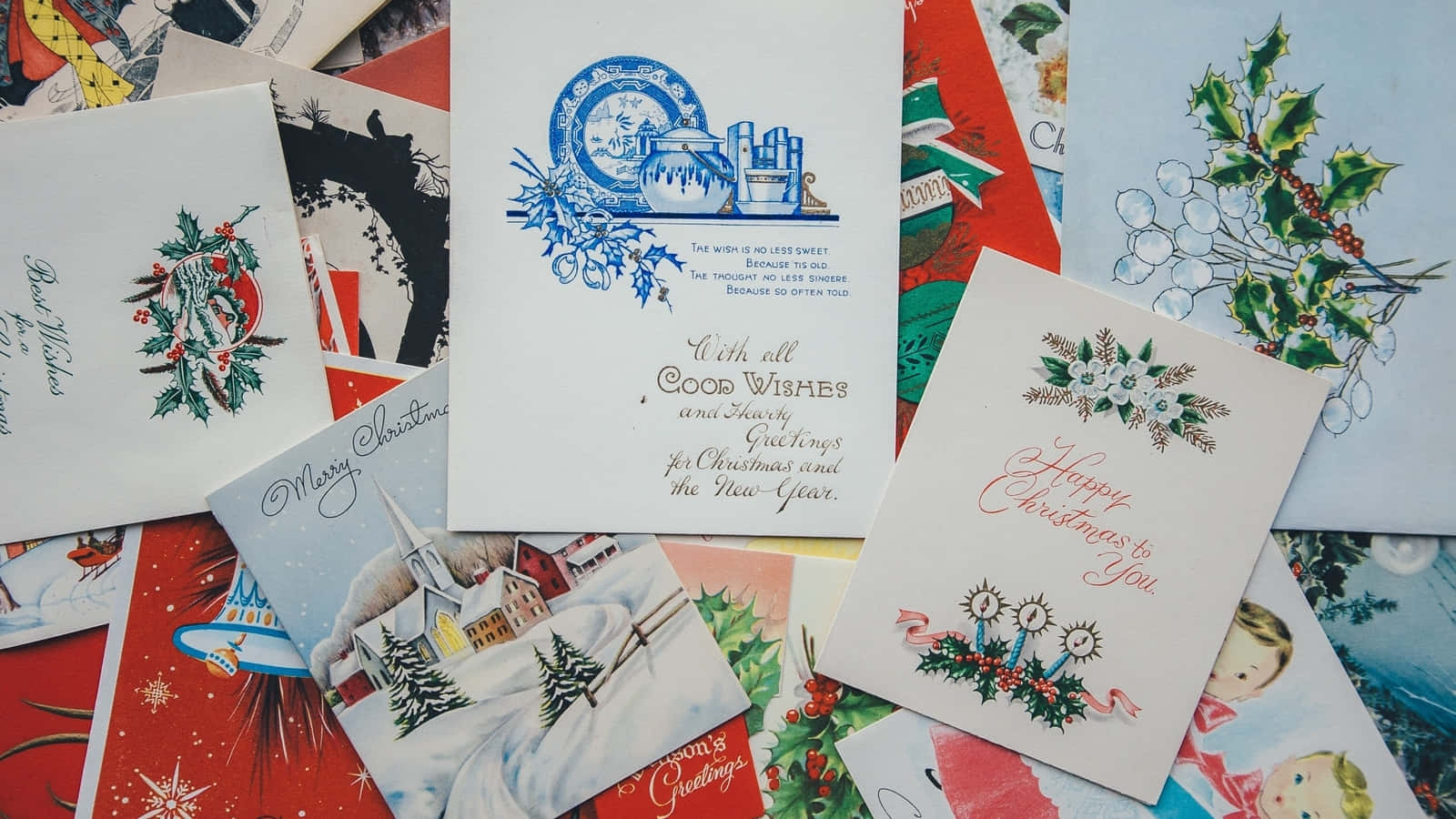 Christmas Card 桌布 壁紙 — 復古聖誕卡，帶有冬青漿果、雪花和節日插圖，散落在色彩繽紛的懷舊堆中。
