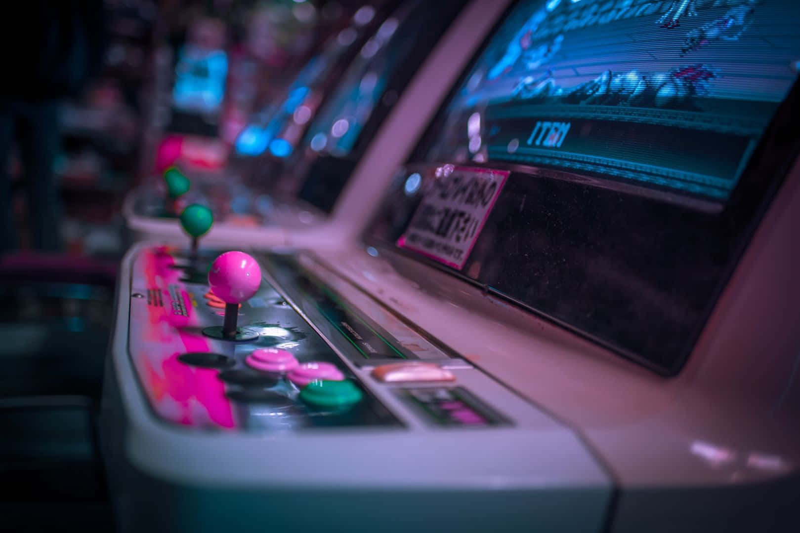 Arcade Games 桌布 壁紙 — 復古街機遊戲的特寫，在霓虹燈下帶有發光的粉紅色操縱桿和彩色按鈕。
