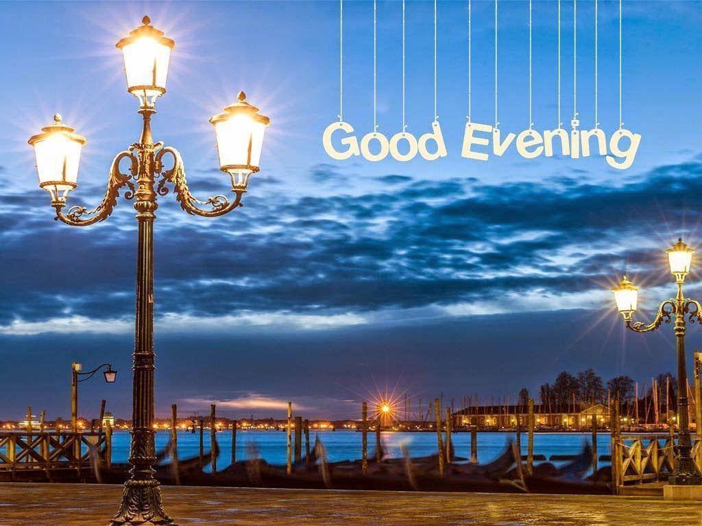 Evening 桌布 壁紙 — 復古路燈在暮色天空中溫暖地發光，而「Good Evening」懸掛在寧靜的海濱場景上方。