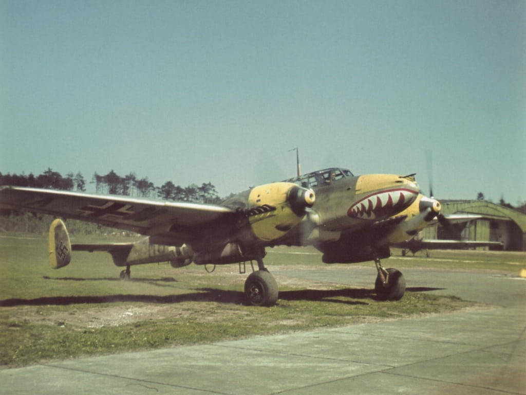Aircraft 桌布 壁紙 — 復古軍用飛機帶有鯊魚嘴鼻藝術，停在停機坪上，藍天白雲，靠近機庫。