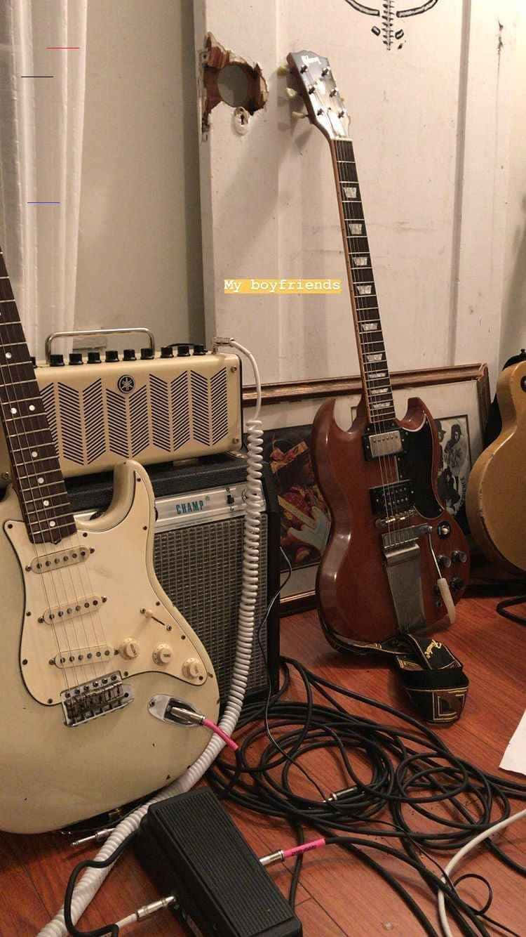 音樂美學 桌布 壁紙 — 復古電吉他和擴音器散落在木地板上，電線纏繞，後面牆上有個洞。