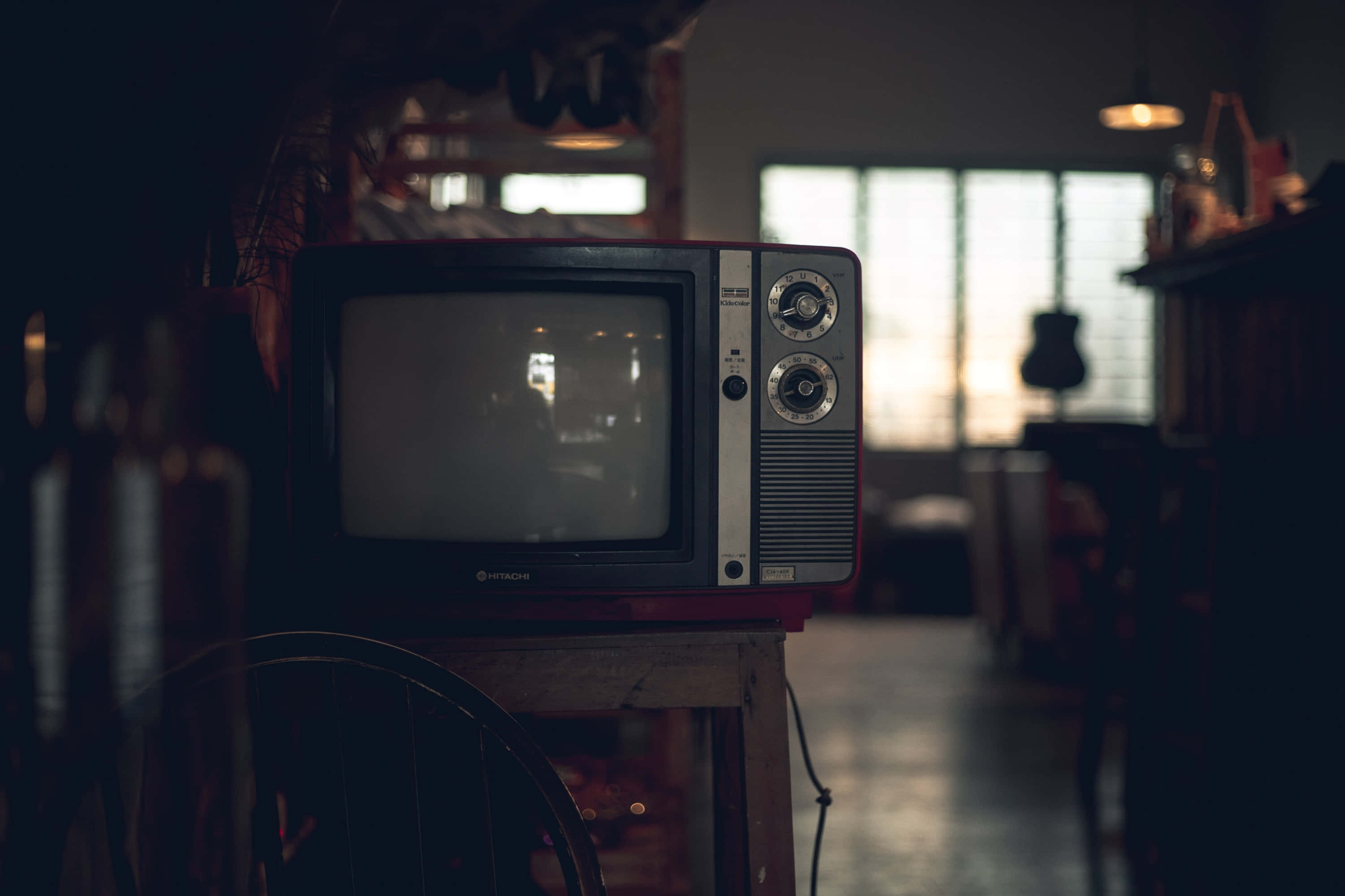 tv 桌布 壁紙 — 復古電視機放在木桌上，房間光線昏暗，柔和光線透過百葉窗照射進來。
