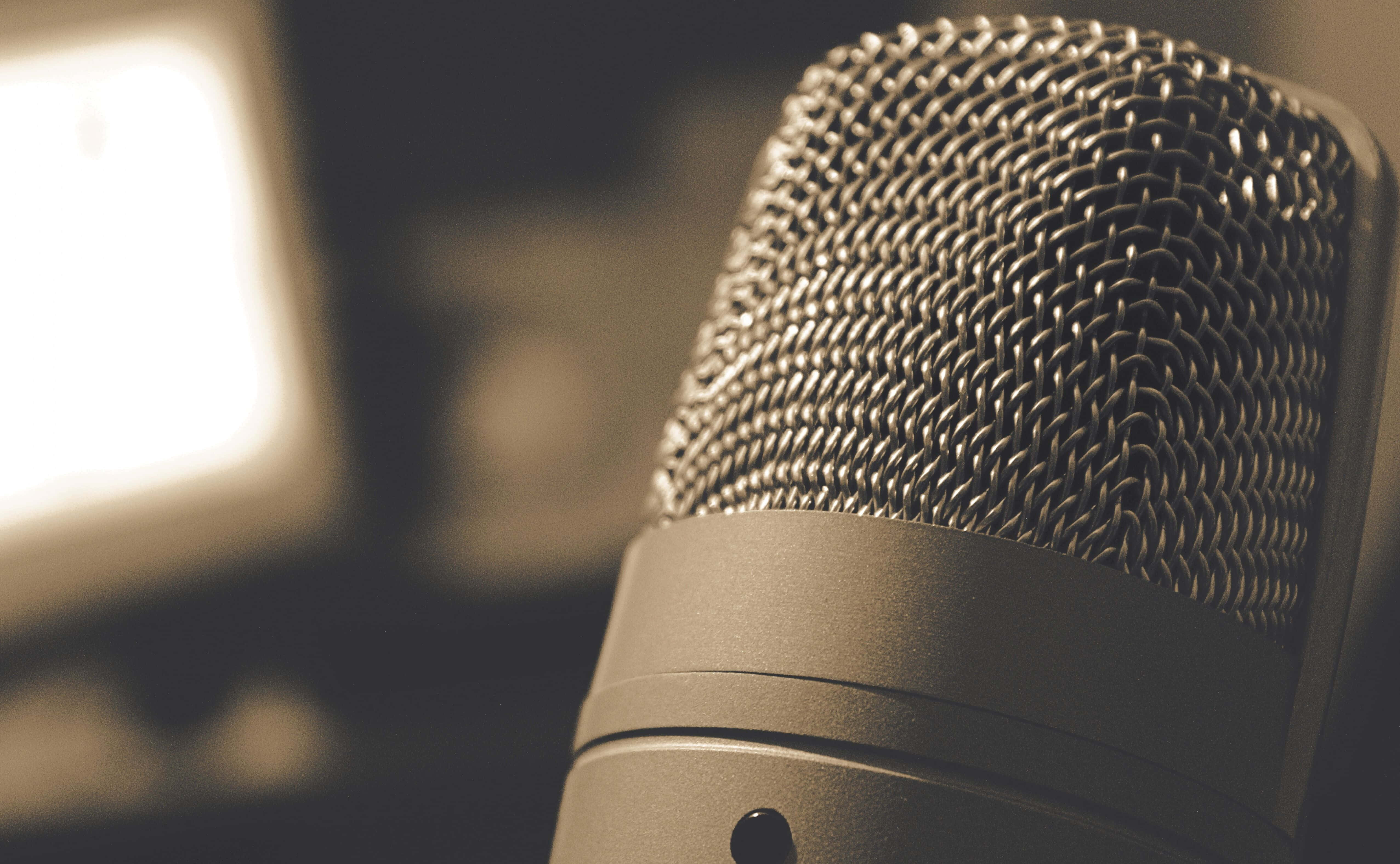 Microphone 桌布 壁紙 — 復古風格麥克風的特寫，金屬網格柵浸浴在溫暖的懷舊色燈光中。
