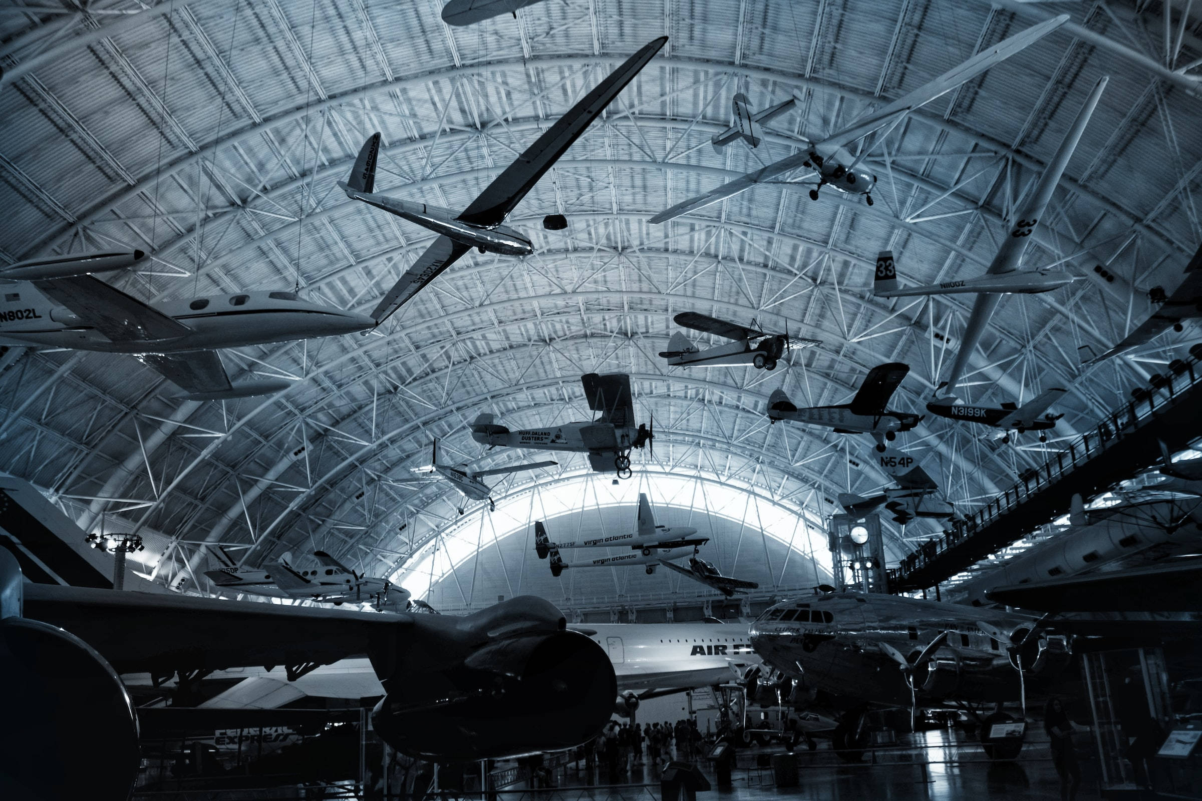 Museum 桌布 壁紙 — 復古飛機懸掛在一個寬敞的工業機庫中，帶有裸露的鋼樑和冷藍色燈光。