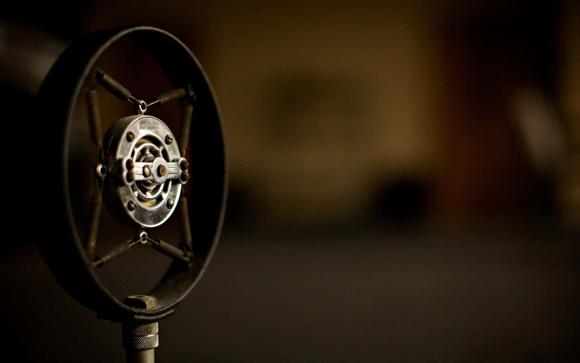 Microphone 桌布 壁紙 — 復古麥克風的特寫，帶有金屬格柵和彈簧，背景柔和模糊的暖色調。