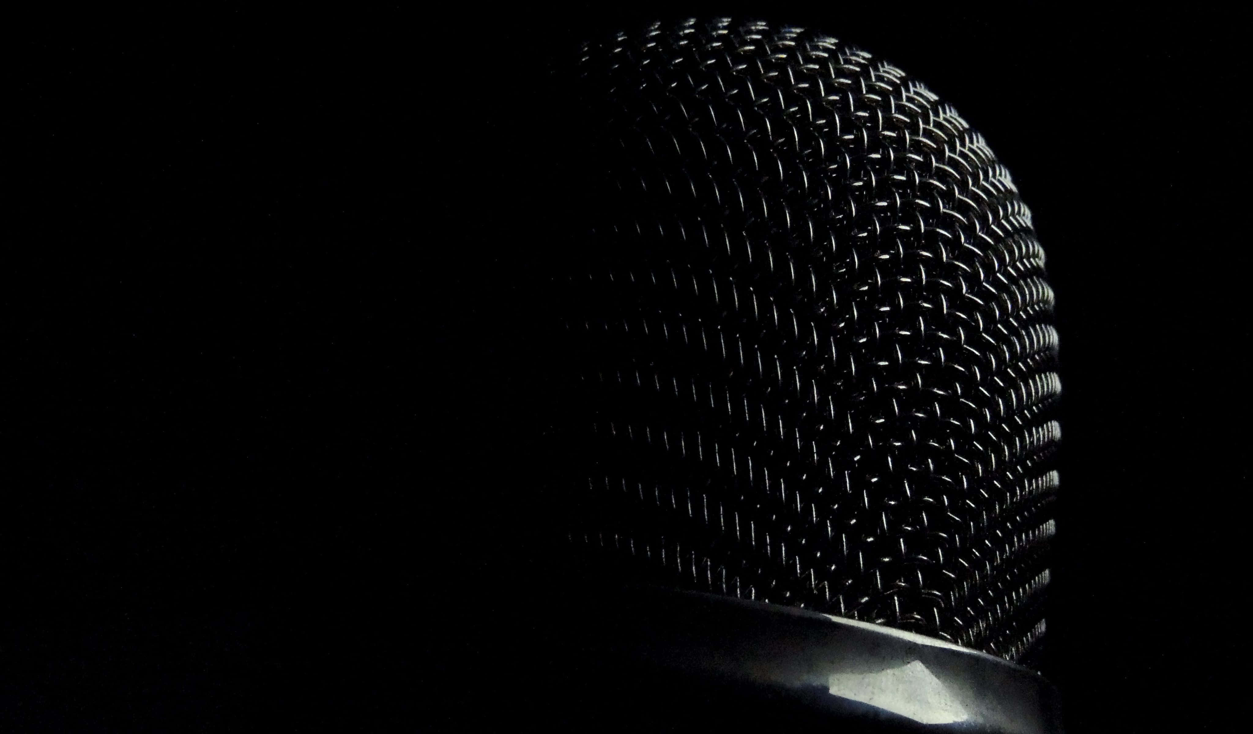 Microphone 桌布 壁紙 — 復古麥克風金屬網格特寫，在漆黑背景下被照亮。