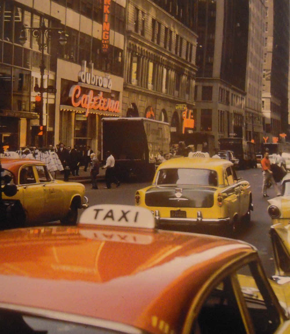 Aesthetic Retro 桌布 壁紙 — 復古黃色計程車在繁華的城市街道上行駛，街道兩旁是高樓大廈，行人靠近發光的咖啡館招牌。