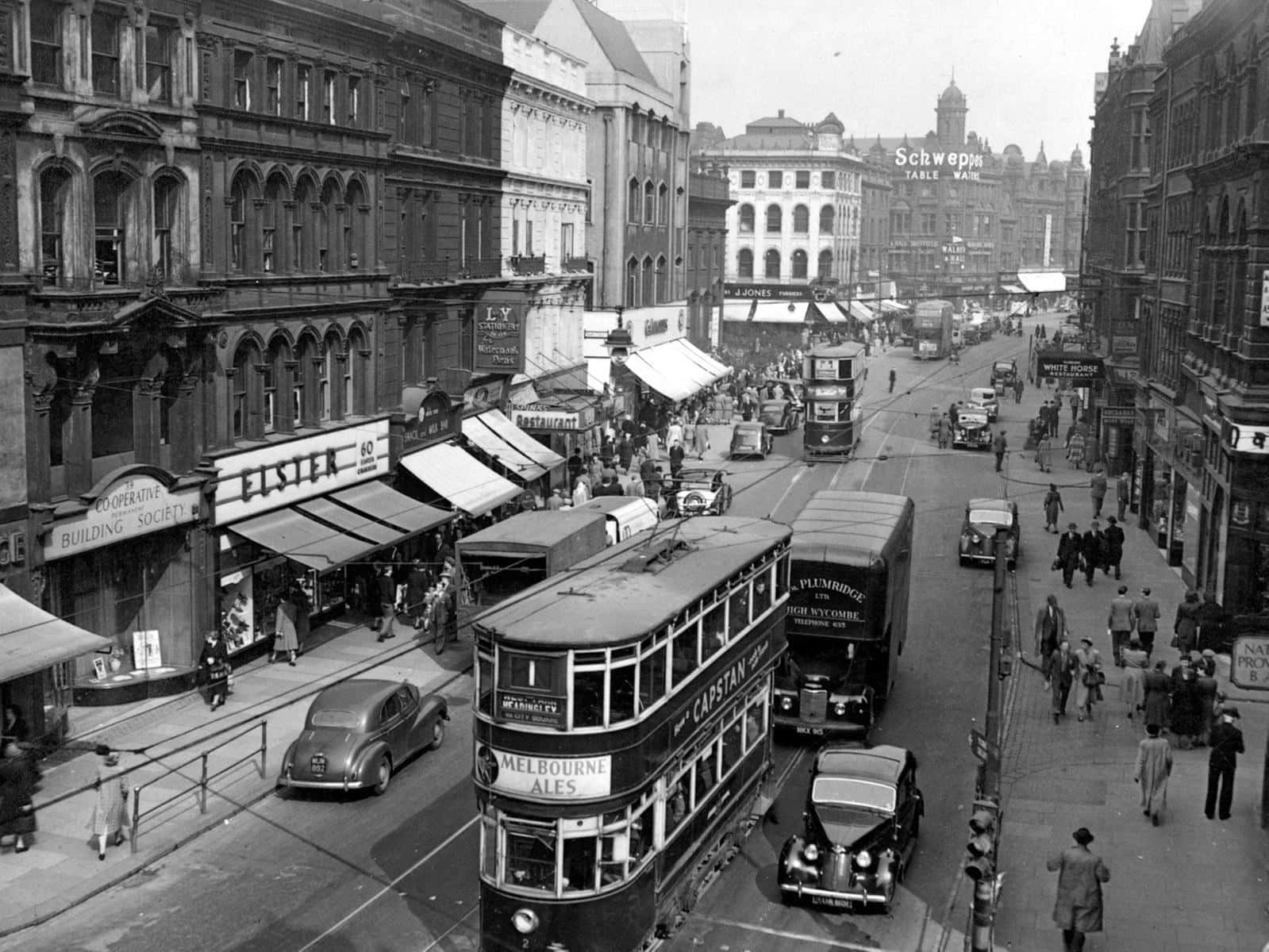 1950s 桌布 壁紙 — 復古黑白街景，雙層電車和經典汽車在繁忙的城市市場中穿梭。