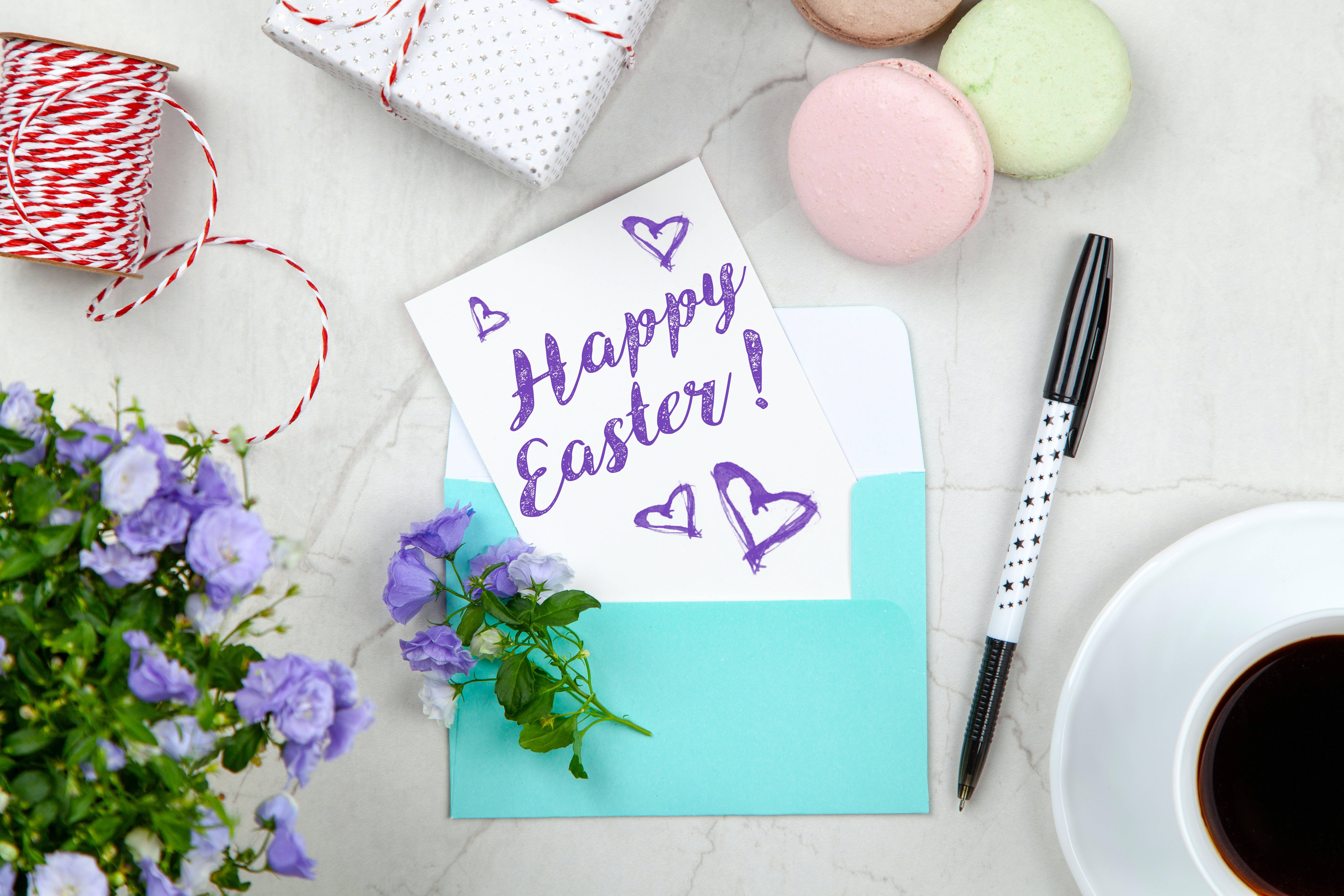 Happy Easter 桌布 壁紙 — 復活節賀卡、馬卡龍、鮮花、咖啡和禮品包裝紙在大理石表面上的平鋪擺放。