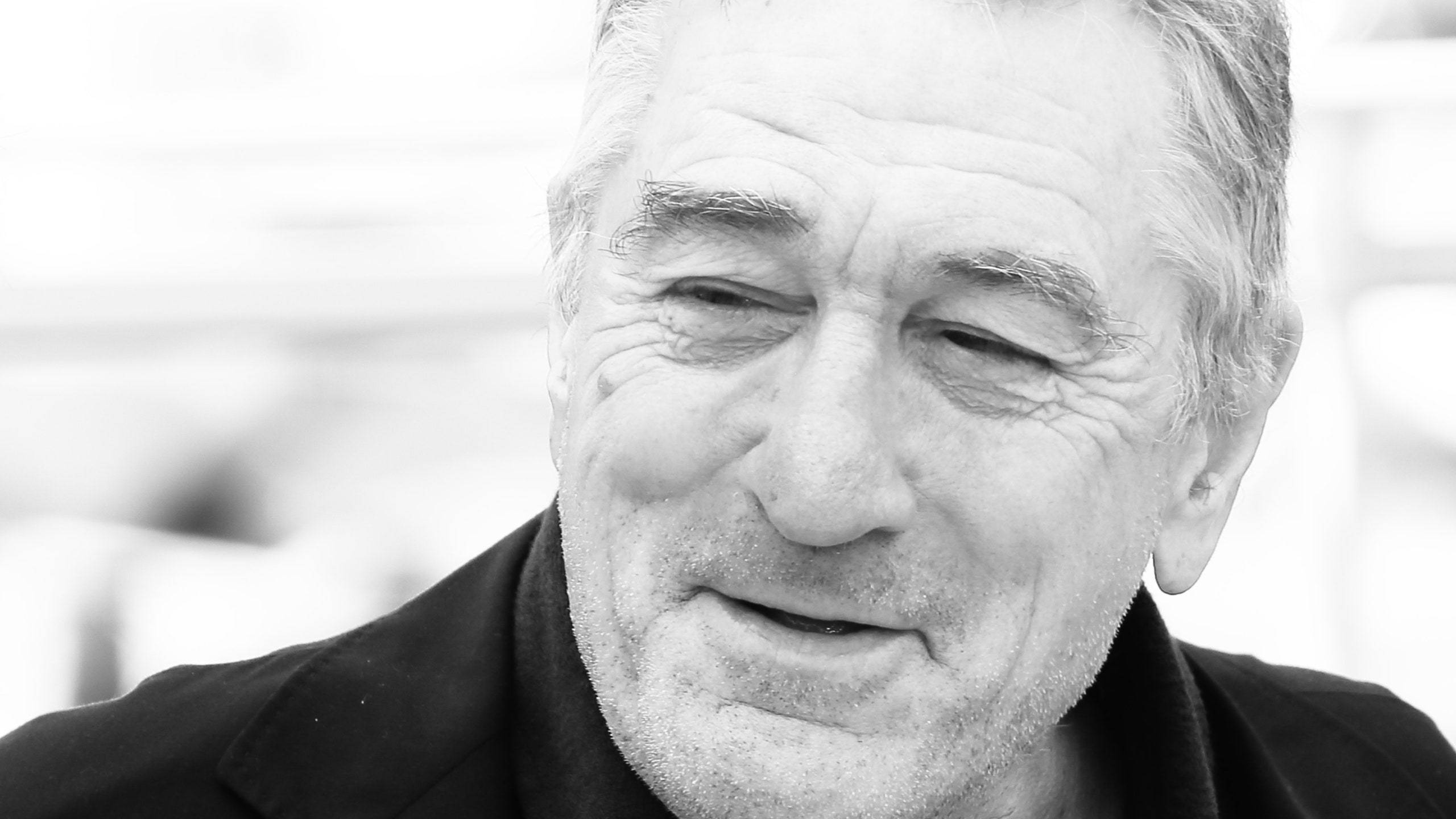 Robert De Niro 桌布 壁紙 — 微笑年長男士的緊密黑白肖像，帶有深皺紋和灰白頭髮。