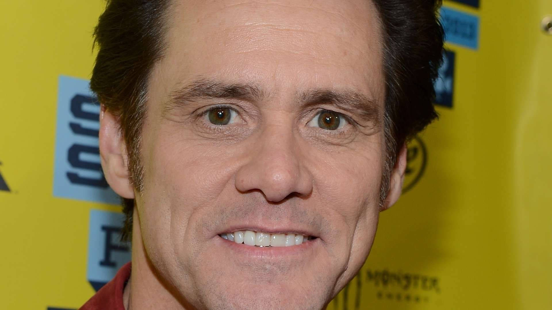 Jim Carrey 桌布 壁紙 — 微笑男士的 close-up 肖像，深色頭髮，棕色眼睛，背景為明亮的黃色品牌背景。