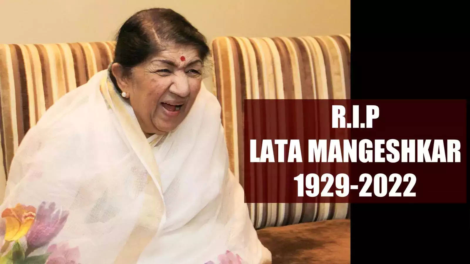 Lata Mangeshkar 桌布 壁紙 — 微笑的Lata Mangeshkar身穿白色花卉圖案紗麗，坐在條紋沙發上，帶有紀念文字疊加。