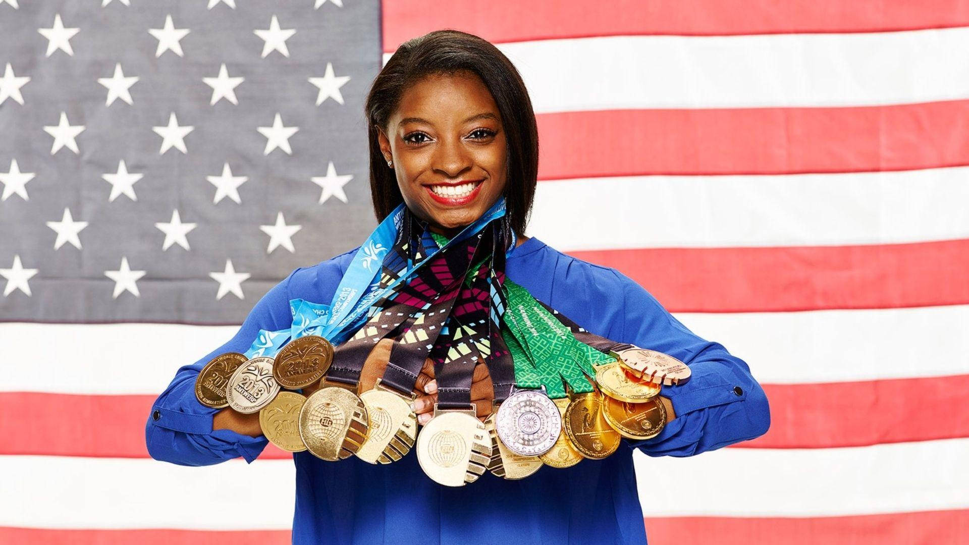 Simone Biles 桌布 壁紙 — 微笑的體操運動員在美國國旗背景下自豪地展示她的奧運獎牌收藏。