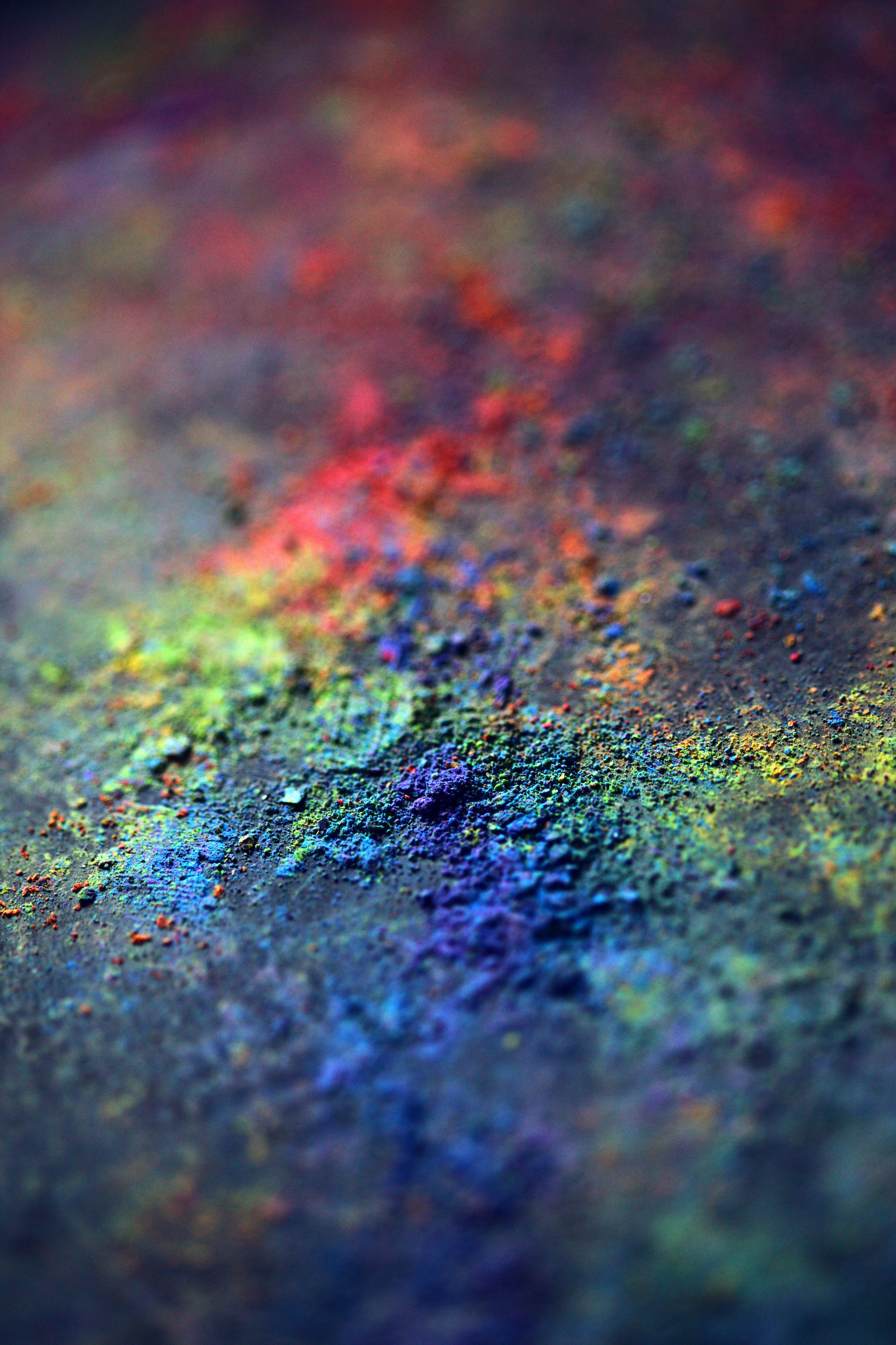 Holi 桌布 壁紙 — 微距拍攝鮮豔彩虹色粉末散落在深色紋理表面上，景深較淺。
