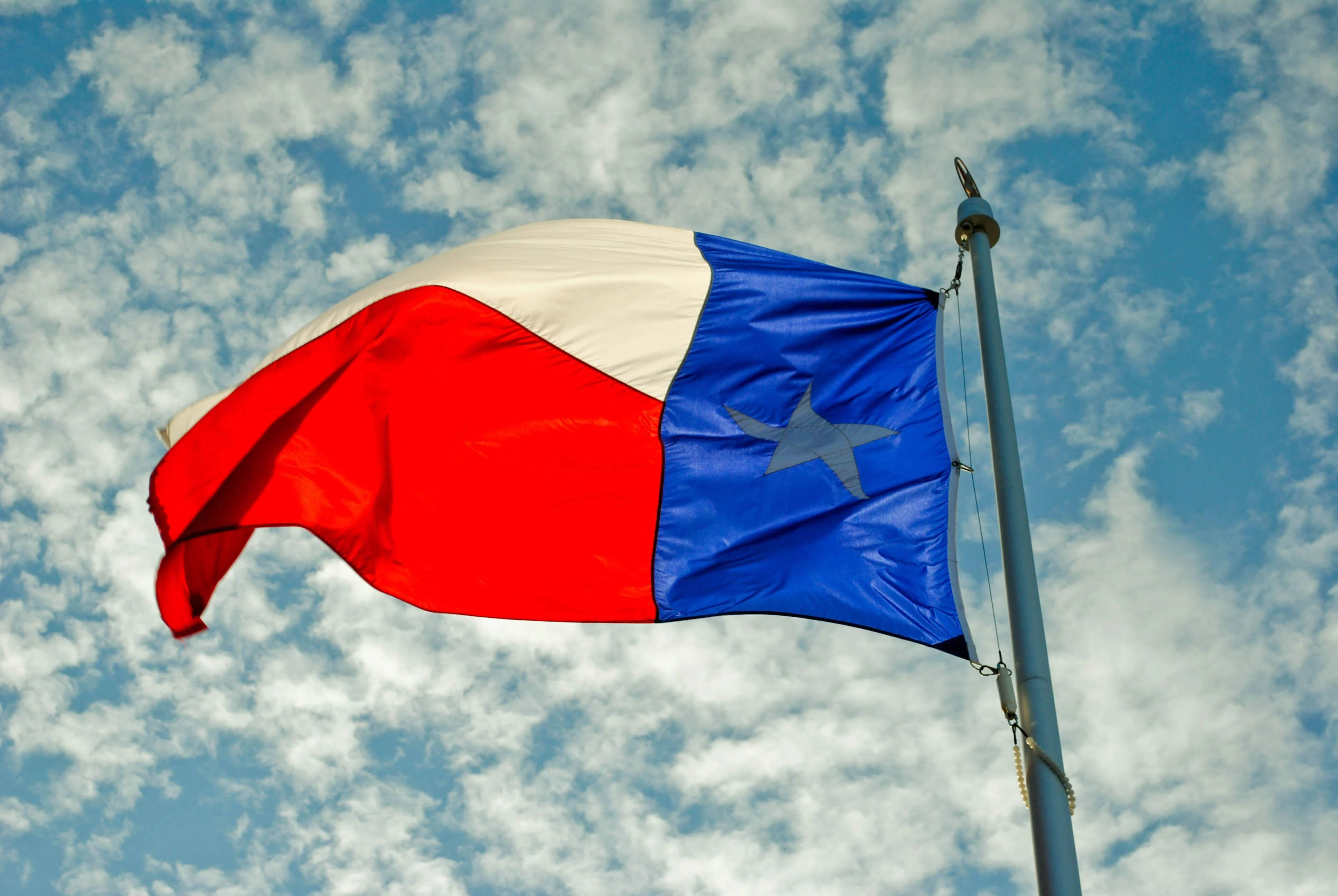 Flag 桌布 壁紙 — 德州州旗在點綴著蓬鬆白雲的明亮藍天中驕傲地飄揚。