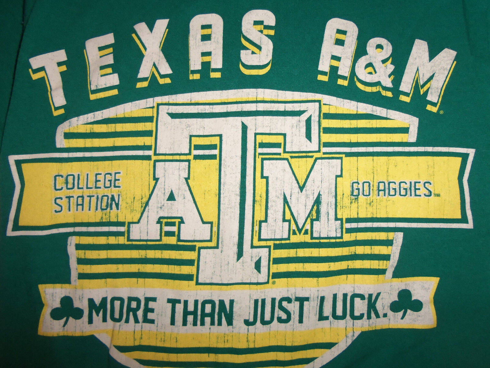 Texas 桌布 壁紙 — 德州農工大學綠色T恤特寫，帶有粗體黃白復古風格標誌和文字。