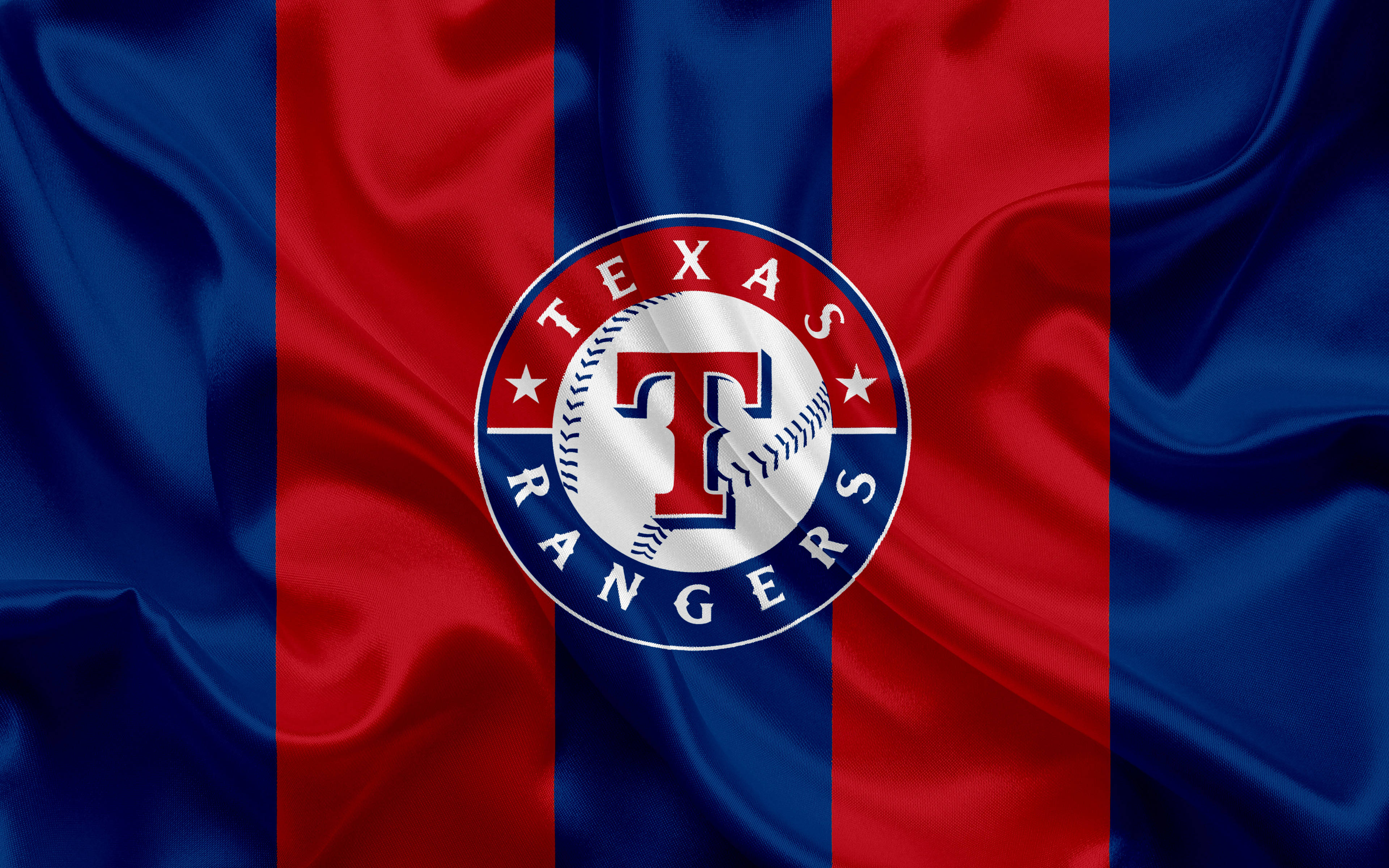 Texas Rangers 桌布 壁紙 — 德州遊騎兵棒球標誌居中於紅藍條紋緞面旗幟上，帶有流動布料質感。