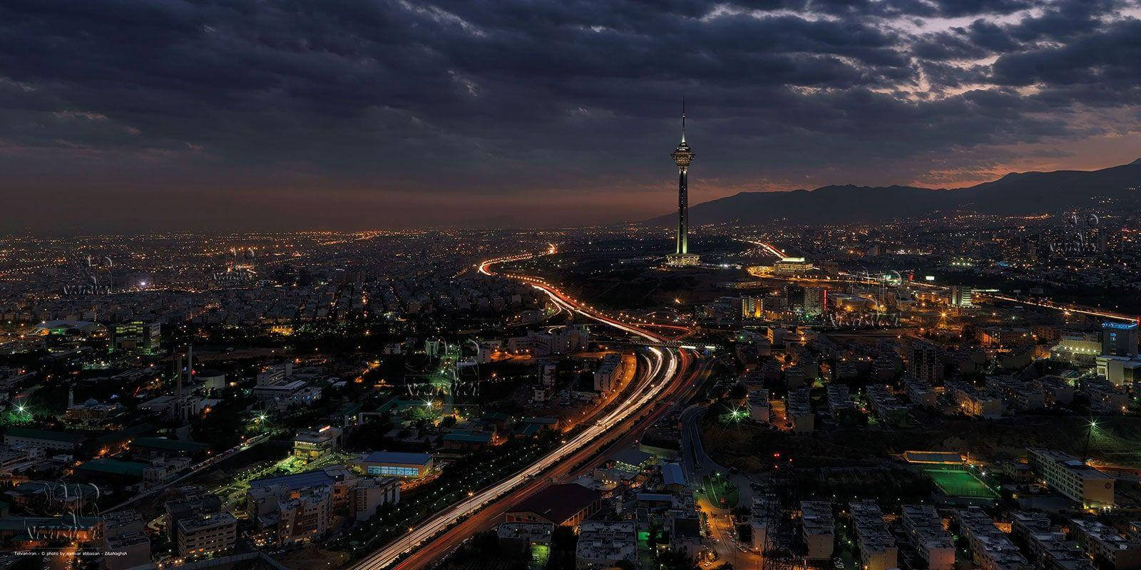 Tehran 桌布 壁紙 — 德黑蘭黃昏的鳥瞰圖，米拉德塔在戲劇性的多雲天空和閃爍的城市燈光中亮起。