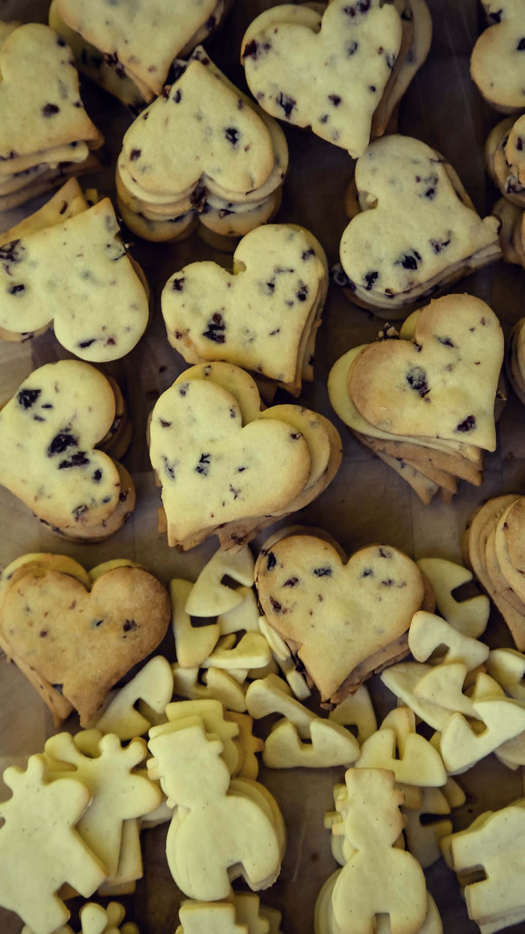 Cookie 桌布 壁紙 — 心形和拼圖塊形狀的餅乾，上面散落著黑巧克力片，放在烘焙紙上。