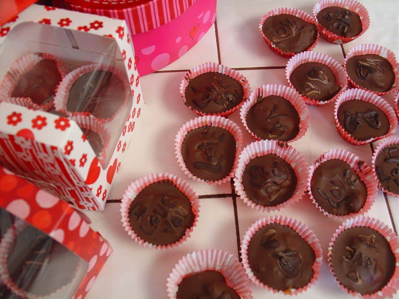 Chocolate 桌布 壁紙 — 心形巧克力糖果放在粉紅色紙杯蛋糕襯墊上，散落在瓷磚表面，旁邊有裝飾盒。