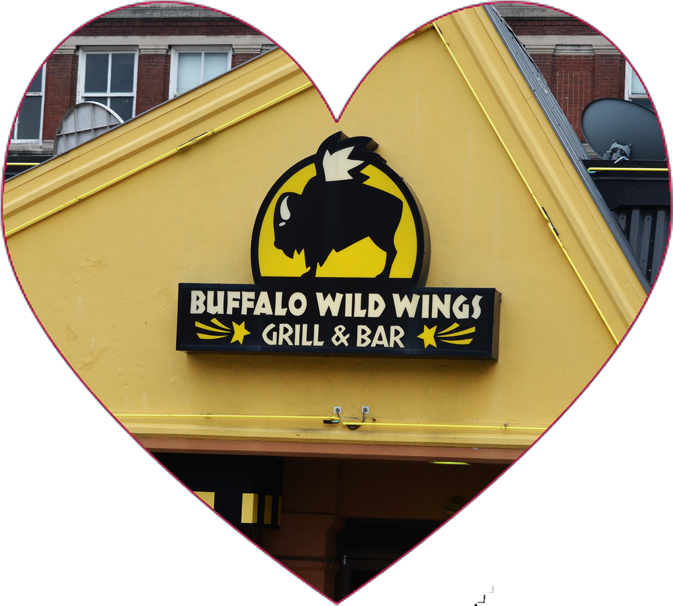 水牛 桌布 壁紙 — 心形框架凸顯了 Buffalo Wild Wings 餐廳招牌，黃色背景上有黑色野牛標誌，襯托著磚砌建築外牆。