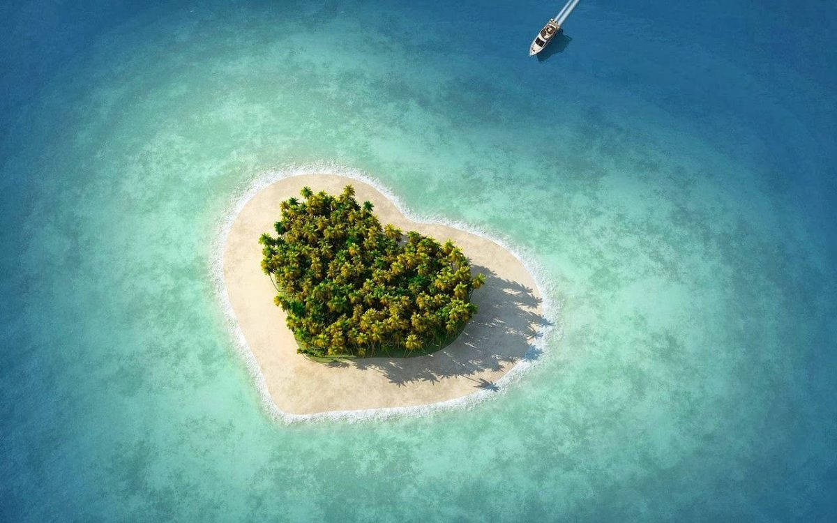 Island 桌布 壁紙 — 心形熱帶島嶼的鳥瞰圖，島上棕櫚樹環繞，周圍是碧綠的海水，附近有一艘遊艇航行。