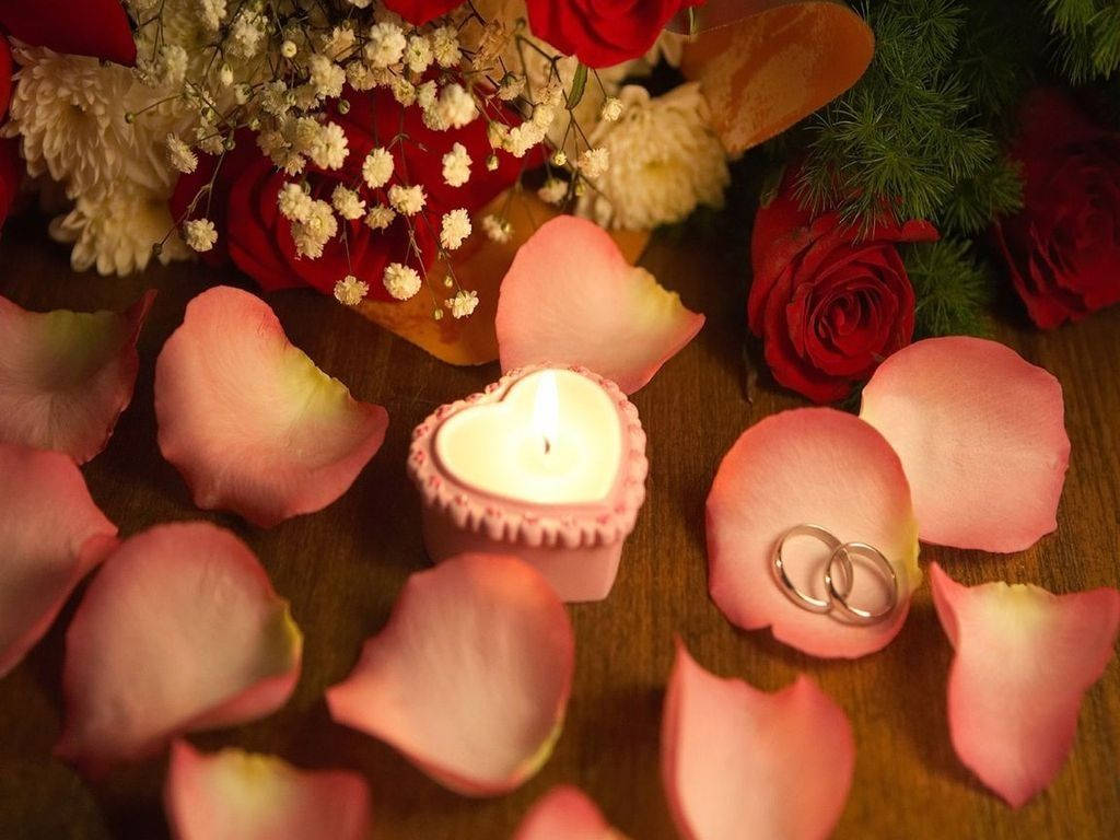 花 桌布 壁紙 — 心形蠟燭在木質表面上，在散落的玫瑰花瓣和結婚戒指之間溫暖地發光。