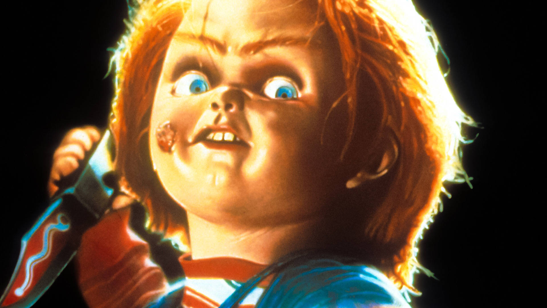 play 桌布 壁紙 — 恐怖娃娃 Chucky 的特寫，藍色大眼睛，手持刀，背景為黑色。
