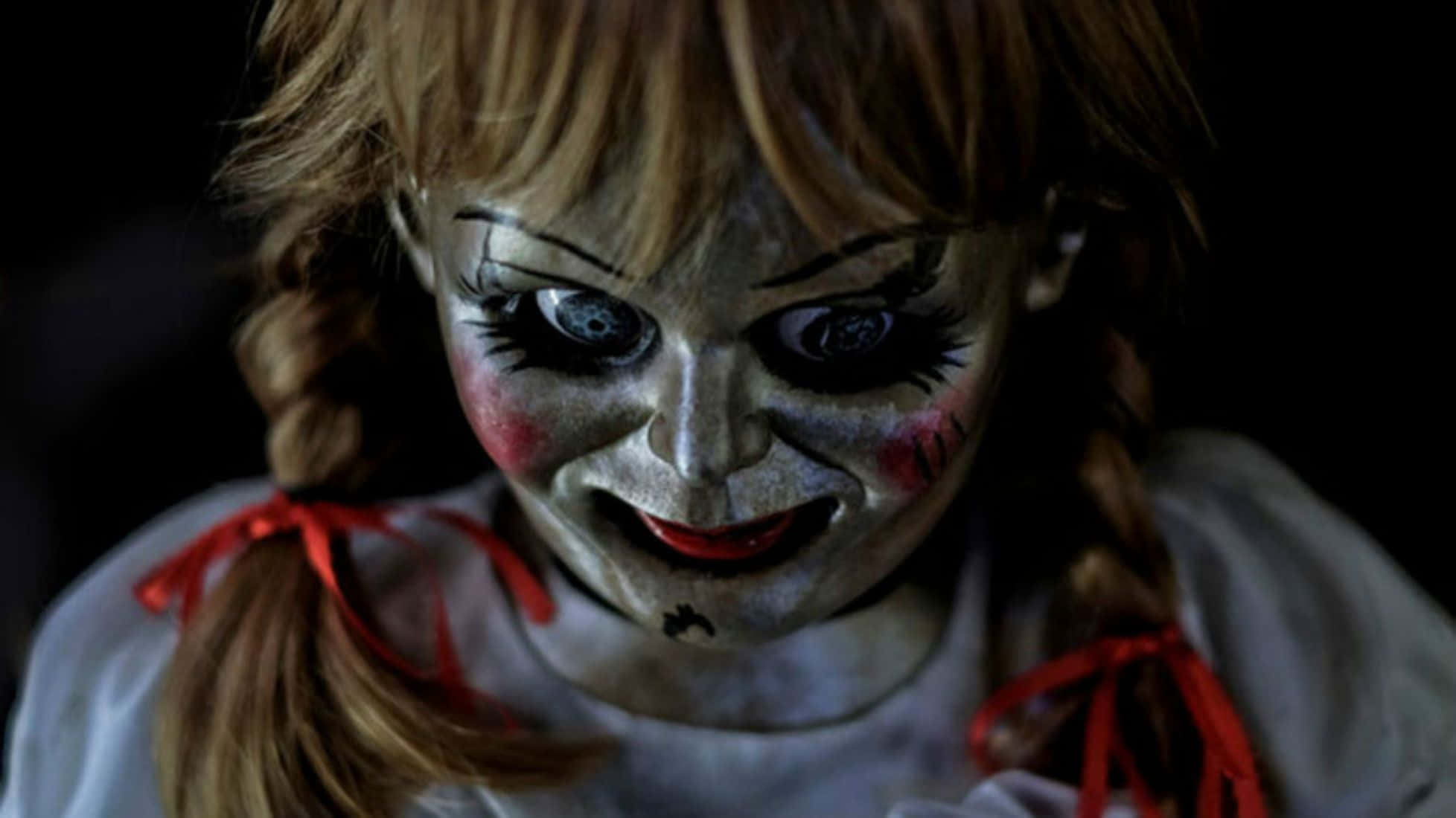 Annabelle 桌布 壁紙 — 恐怖娃娃特寫，蒼白的臉、紅唇和辮子頭髮，背景黑暗。