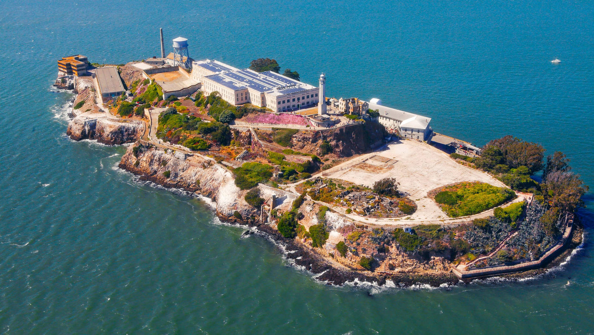 Island 桌布 壁紙 — 惡魔島的鳥瞰圖，歷史悠久的監獄建築被碧綠的海水和岩石海岸環繞。