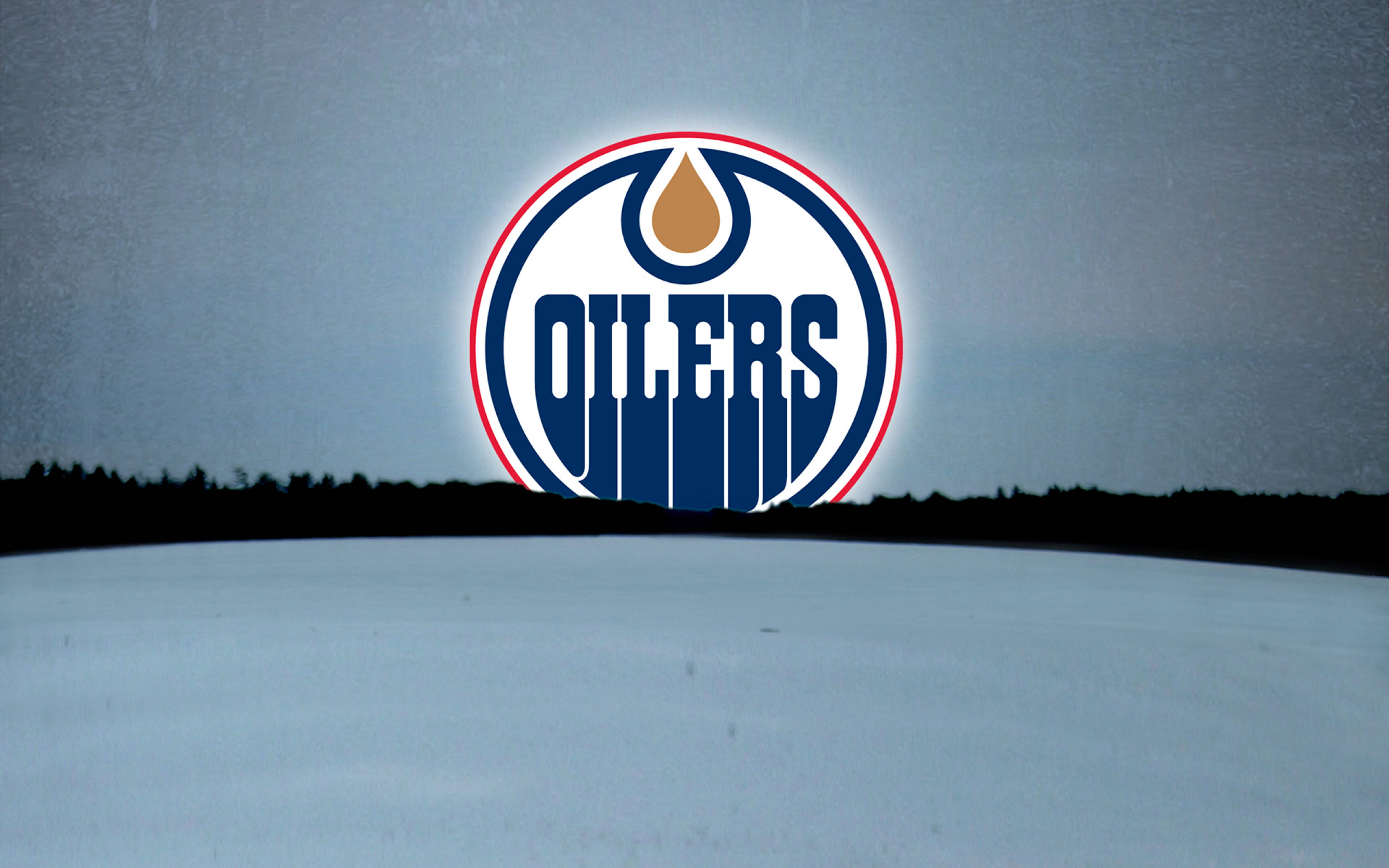 Oilers 桌布 壁紙 — 愛德蒙頓油人隊標誌在灰色天空和深色樹線剪影下的雪景中閃耀。