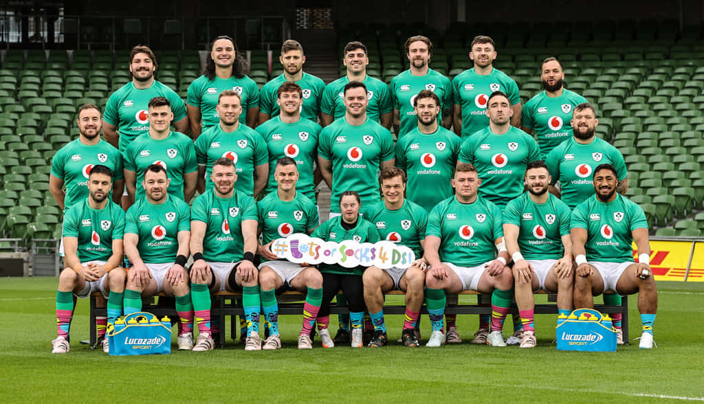 Ireland Rugby 桌布 壁紙 — 愛爾蘭橄欖球隊身穿綠色球衣在球場草地上擺姿勢，身後是空蕩蕩的綠色座位。