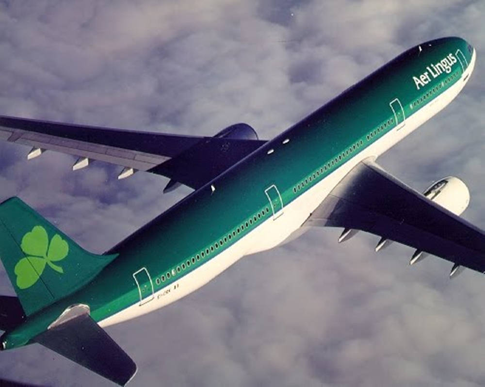  壁紙 — 愛爾蘭航空的空中巴士A330在雲層中翱翔，其綠色三葉草尾翼和青綠色塗裝捕捉光線。