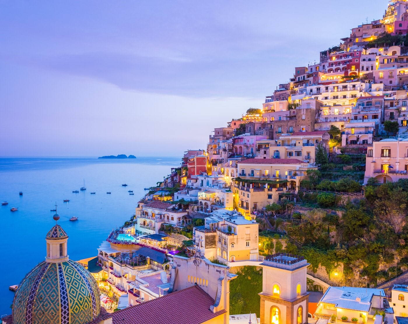 Amalfi Coast 桌布 壁紙 — 懸崖上的海岸小鎮在溫暖燈光下閃耀，暮色將大海和天空染成柔和的藍色和紫色。