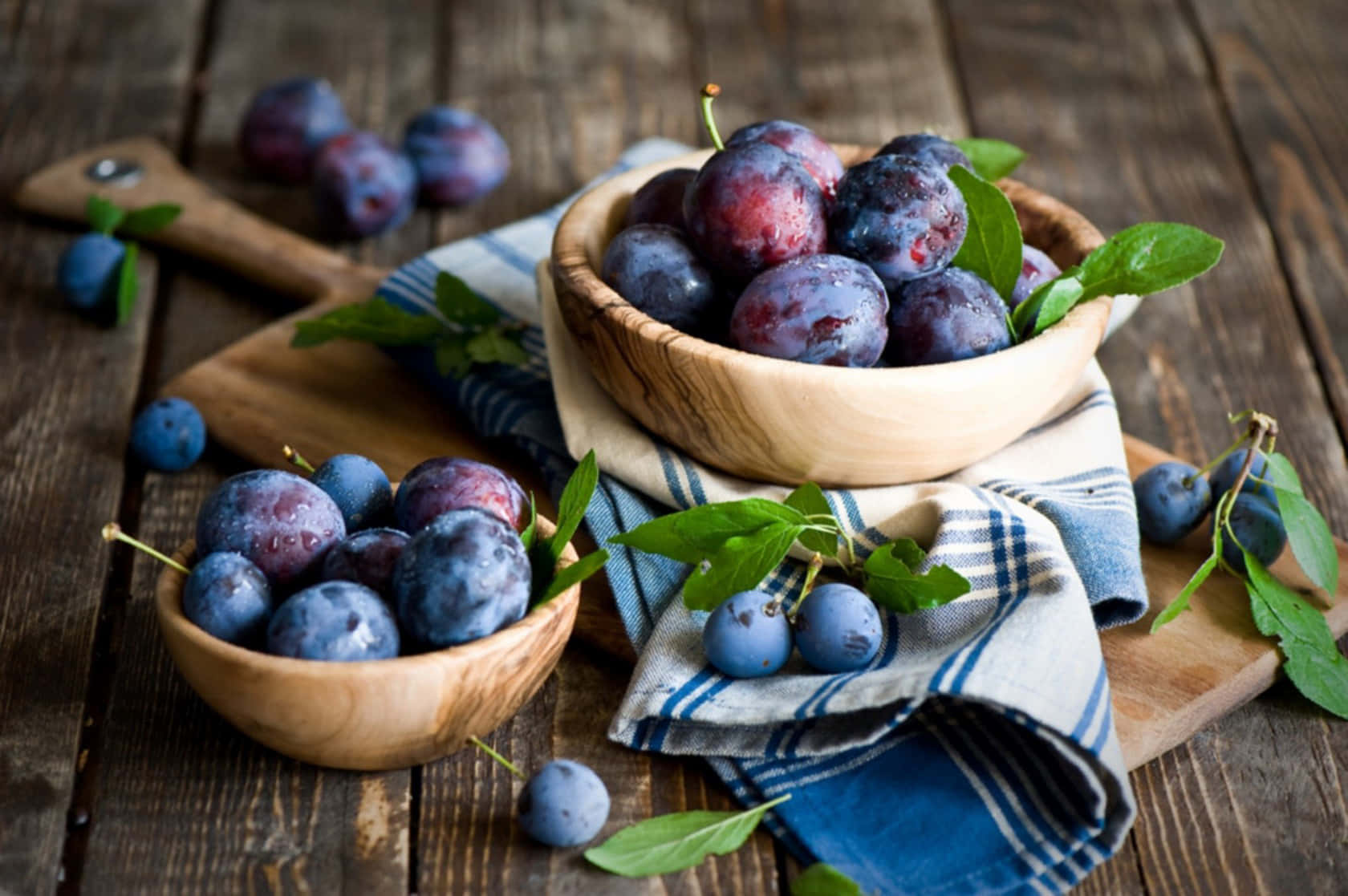 Fruits 桌布 壁紙 — 成熟的李子放在木碗裡，擱在條紋布上，置於質樸的木桌上。