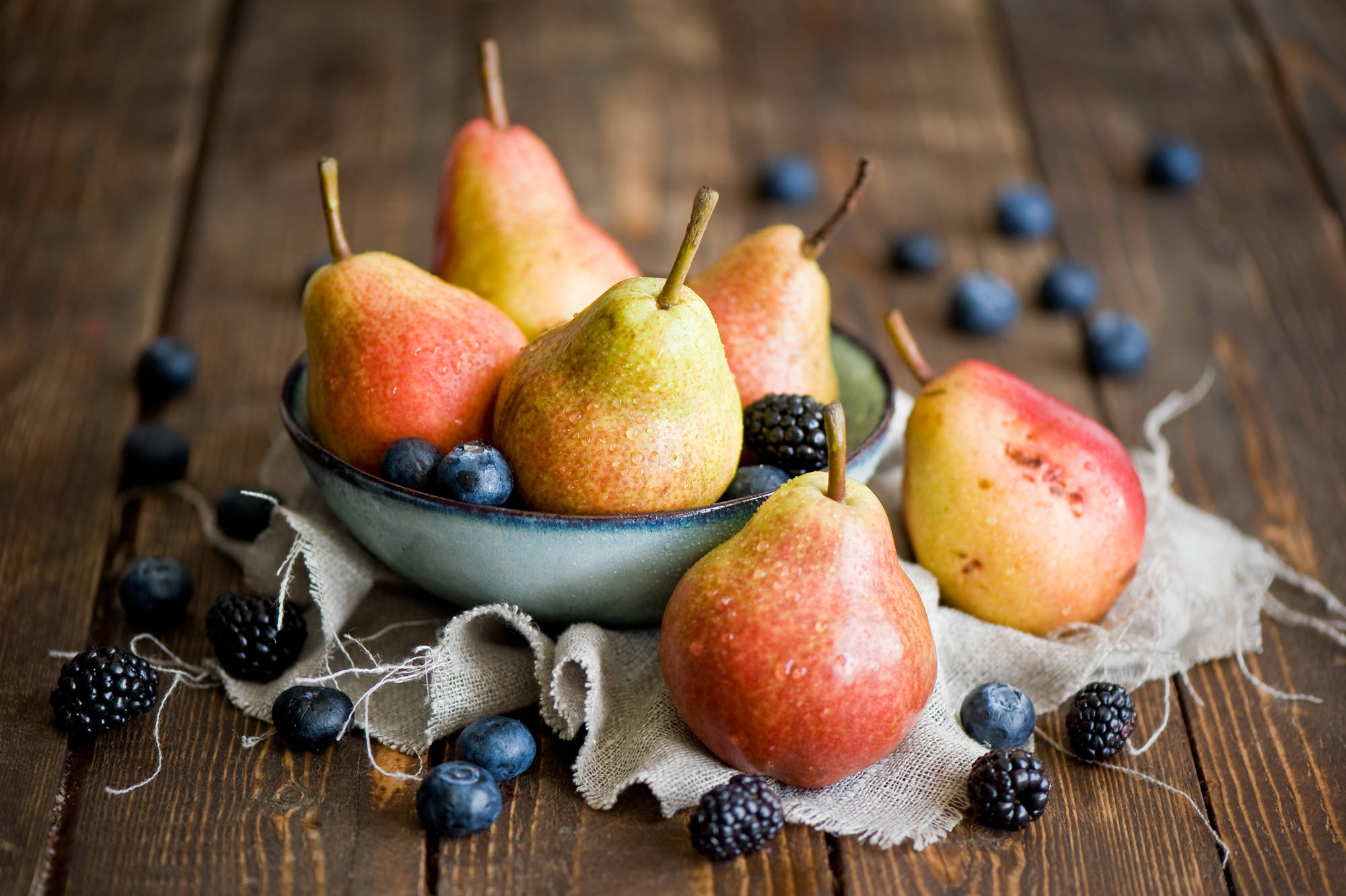Fruits 桌布 壁紙 — 成熟的梨子和漿果放在陶瓷碗中，置於鋪有亞麻布的鄉村風格木桌上。