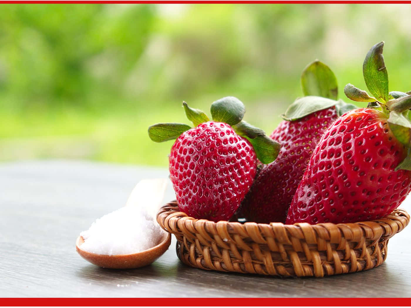 Strawberries 桌布 壁紙 — 成熟的紅色草莓配綠葉放在編織籃中，旁邊有木匙盛著白糖，置於深色木桌上。