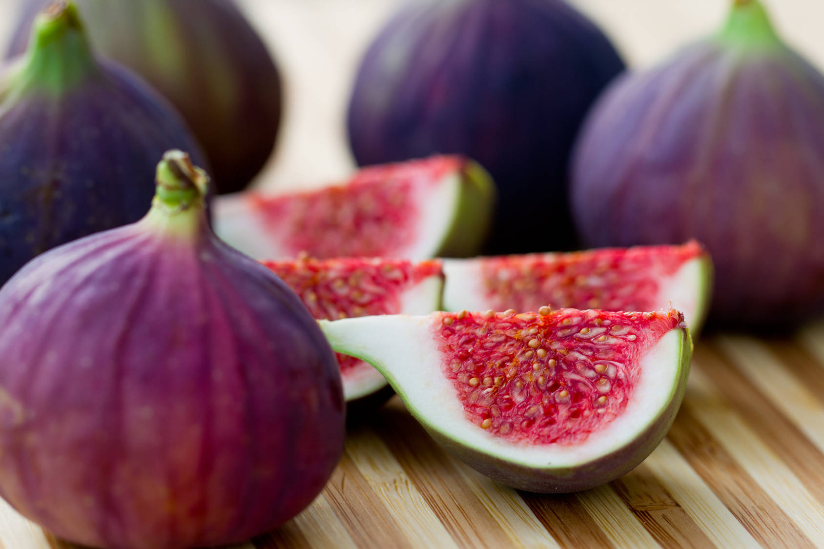 Fruits 桌布 壁紙 — 成熟的紫色無花果，完整和切片，露出粉紅色果肉，放在木板上。