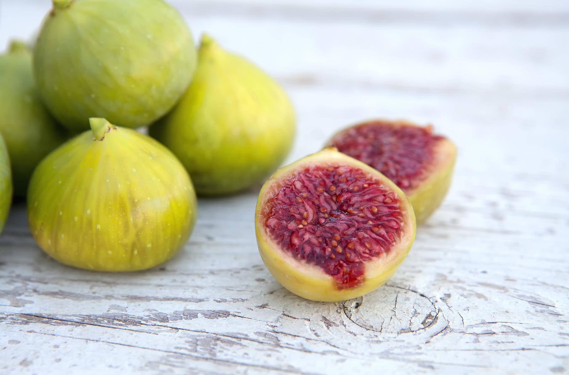 Fruits 桌布 壁紙 — 成熟的綠色無花果，帶有多汁的紅色內部，放在經風化的白色木質表面上。