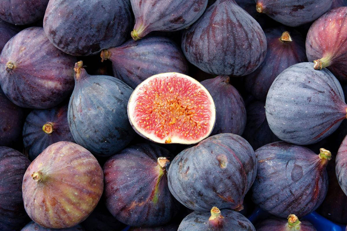 Fruits 桌布 壁紙 — 成熟紫色無花果的特寫，其中一個切開，露出粉紅色果肉和金黃色種子。