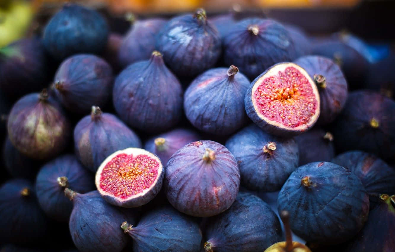 Purple Figs 桌布 壁紙 — 成熟紫色無花果的特寫，有兩個切開一半，露出多汁的粉紅色內部。