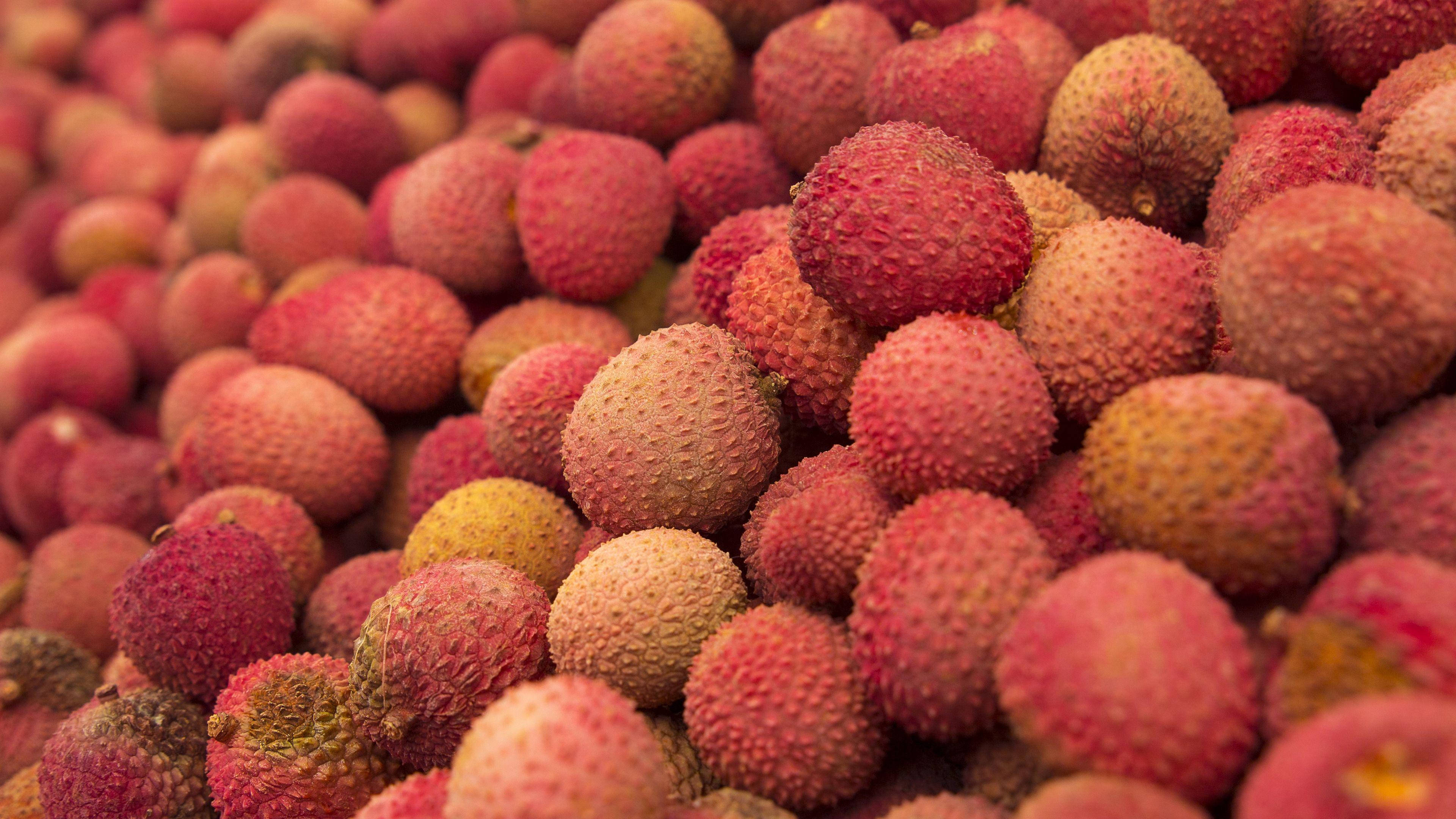Fruits 桌布 壁紙 — 成熟荔枝的鮮豔特寫，帶有紋理的粉紅色外皮堆疊在一起。