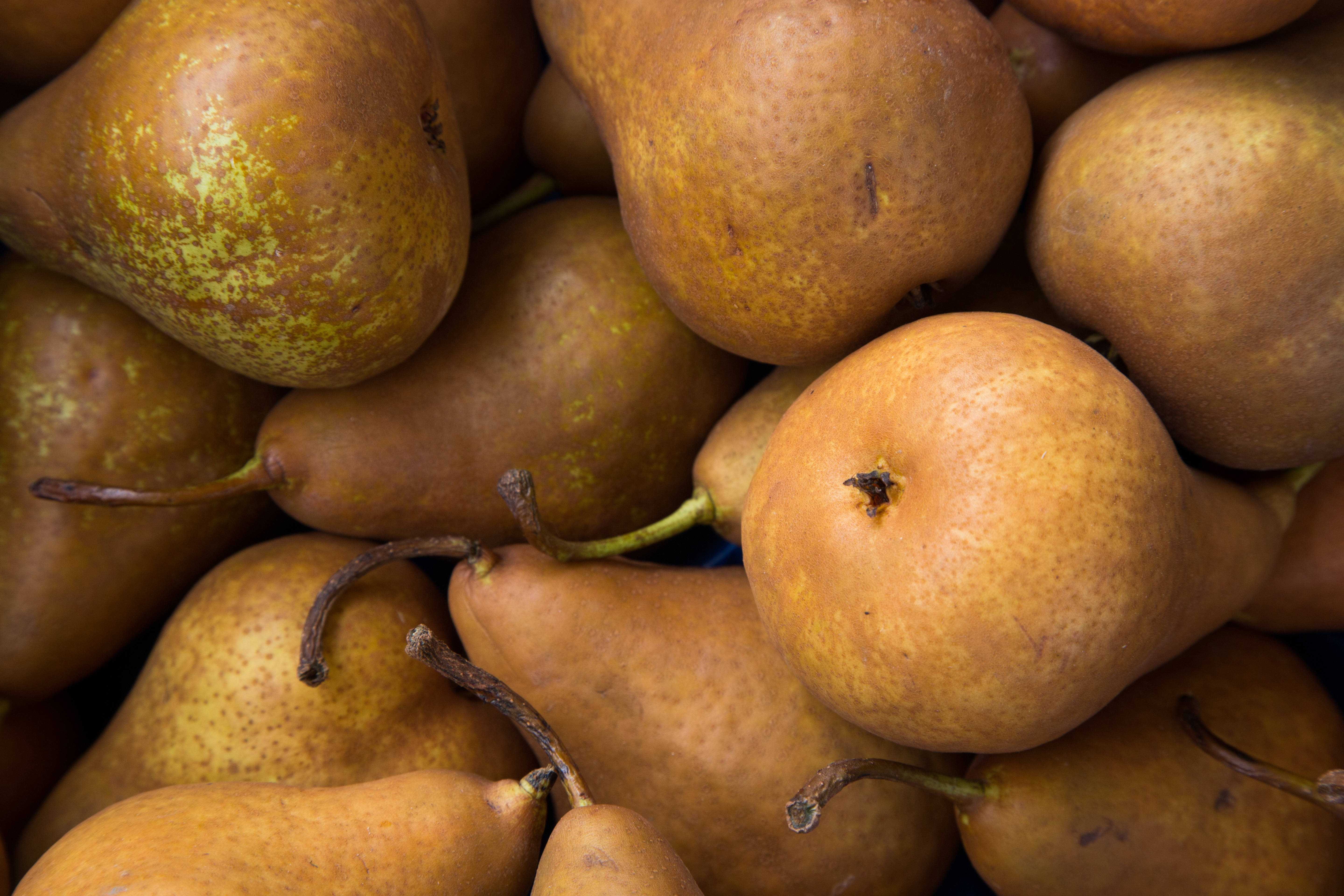 Fruits 桌布 壁紙 — 成熟金黃色梨子帶斑點表皮和莖部堆疊在一起的特寫。