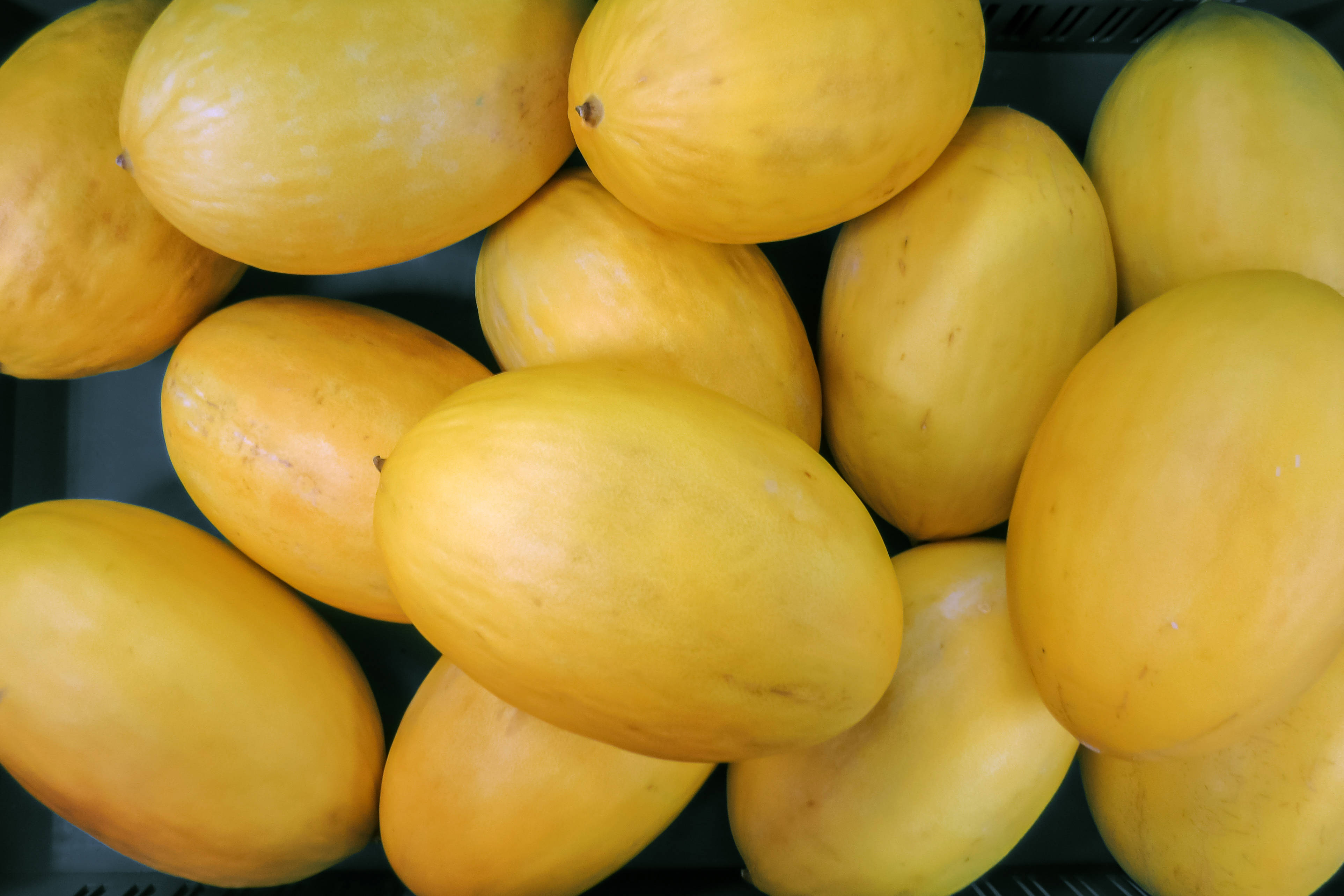 Fruit 桌布 壁紙 — 成熟黃色南瓜堆放在深色托盤中的特寫，帶有柔和自然光。