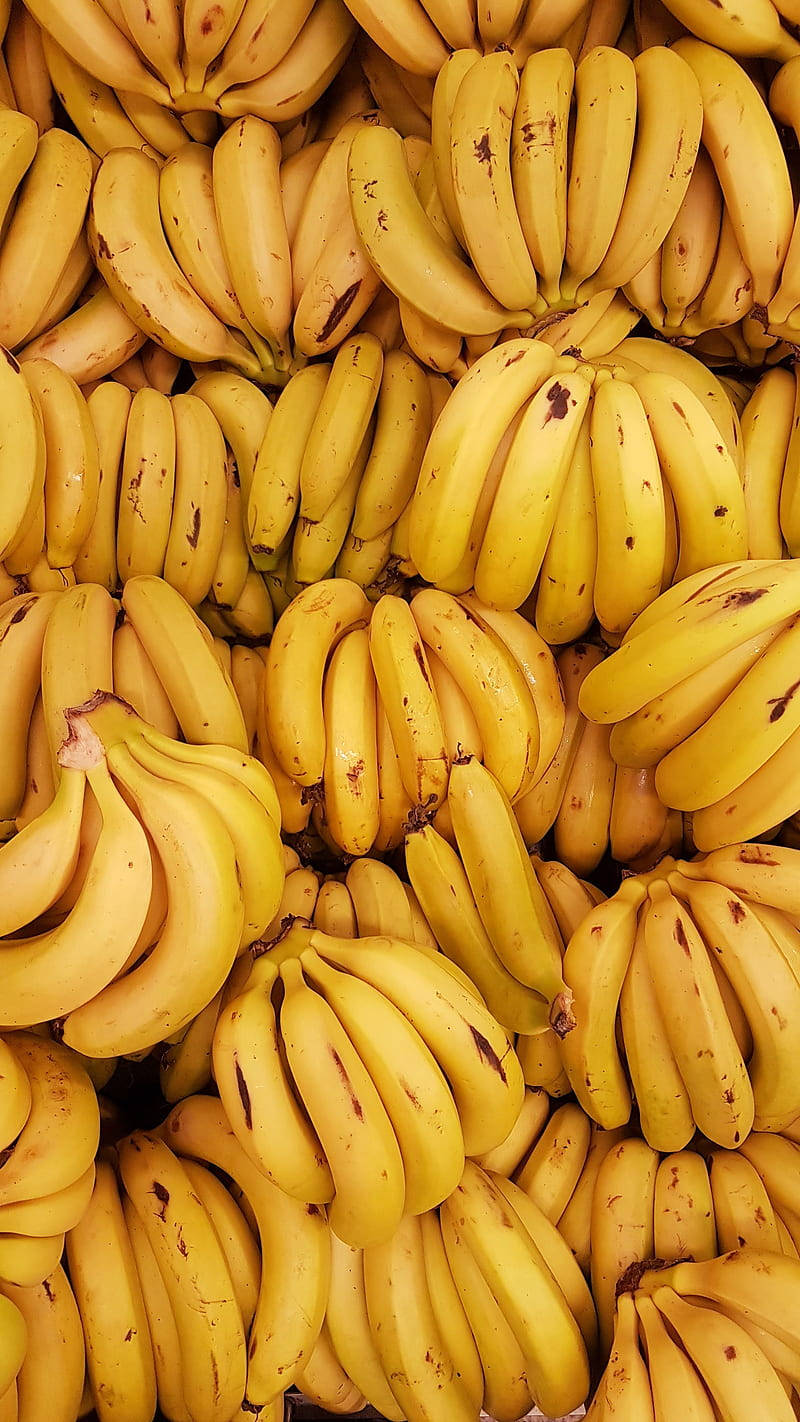 Plantain 桌布 壁紙 — 成熟黃色香蕉密集堆疊、帶有天然褐色斑點的鮮明特寫。