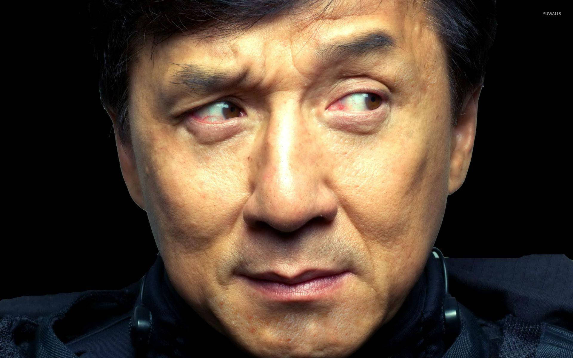 eyebrow raise 桌布 壁紙 — 成龍的特寫肖像，眼神銳利，眉頭緊鎖，背景是黑色。