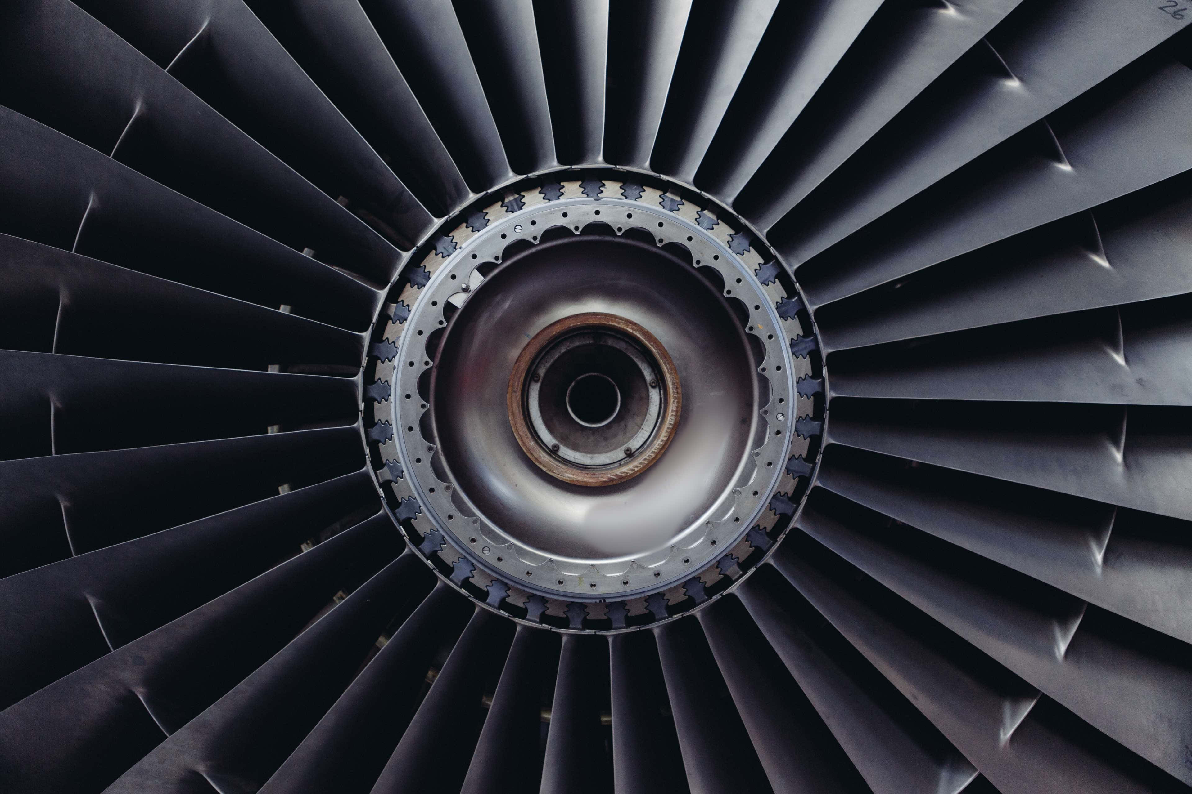 Jet Engine 桌布 壁紙 — 戲劇性燈光下，帶有徑向葉片和金屬中心的噴射引擎渦輪特寫。